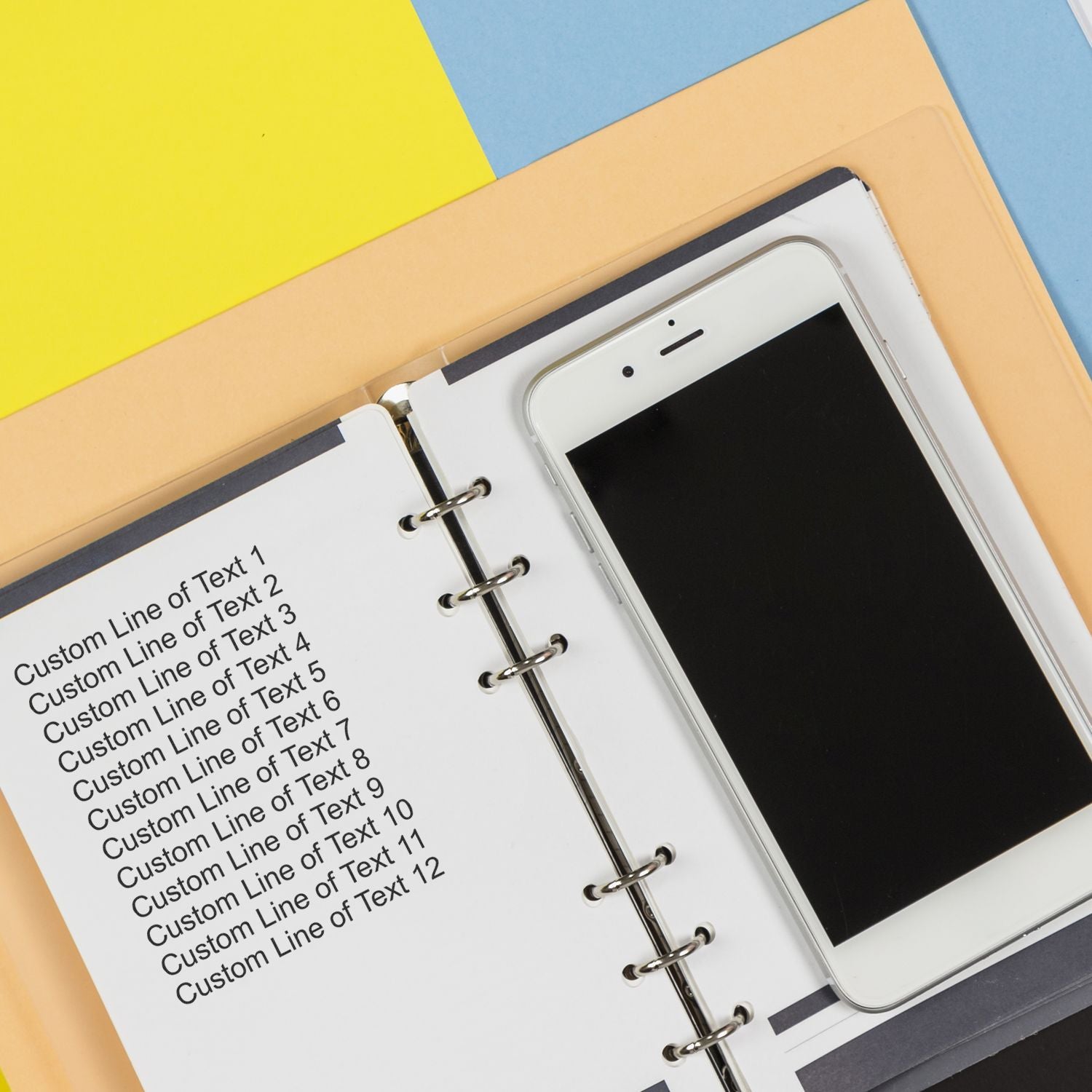 12 Line Custom Rubber Stamp with Wood Handle used on a notebook page beside a smartphone, displaying multiple lines of custom text.