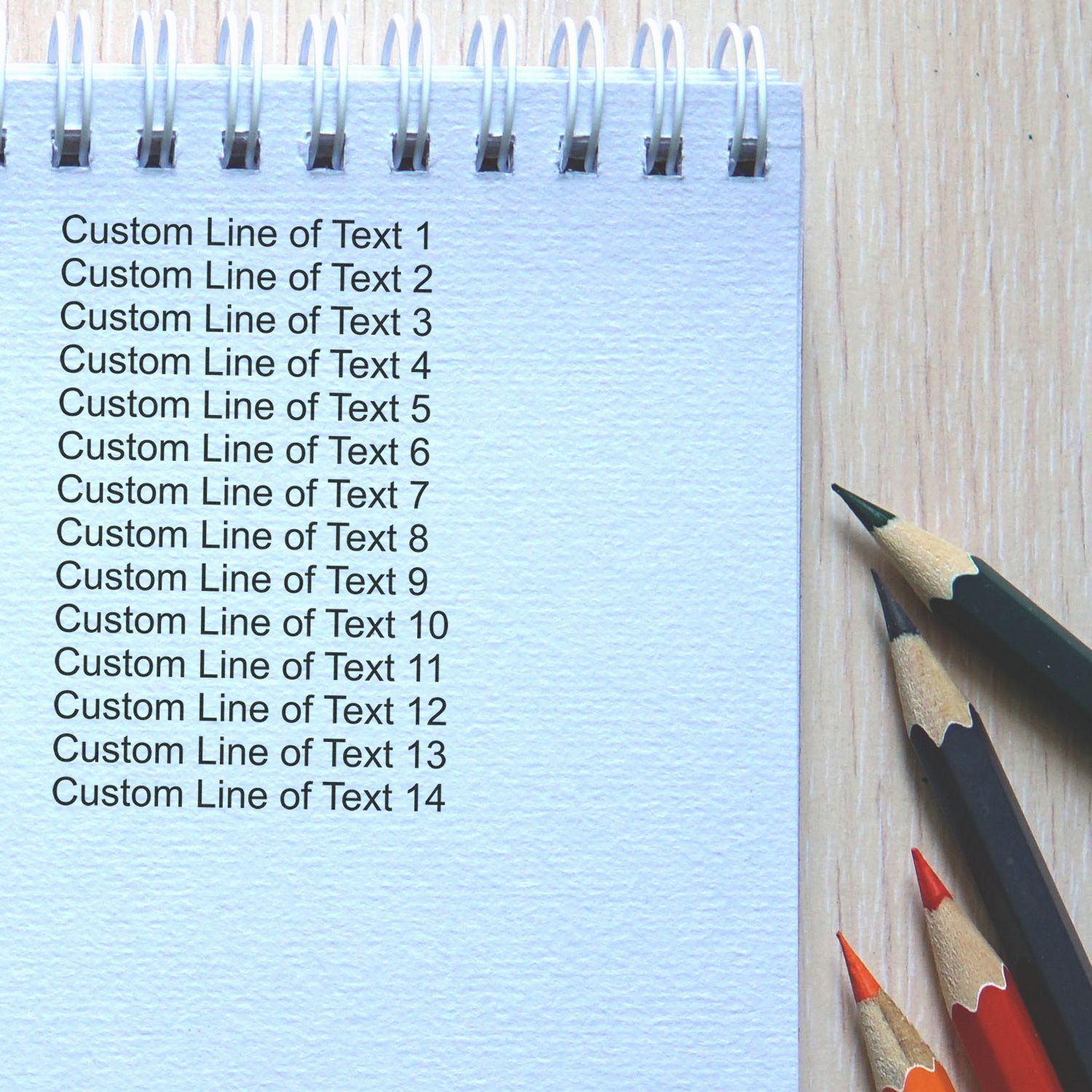 14 Line Custom Rubber Stamp with Wood Handle used on a spiral notebook, showing 14 lines of custom text. Pencils are placed beside the notebook.