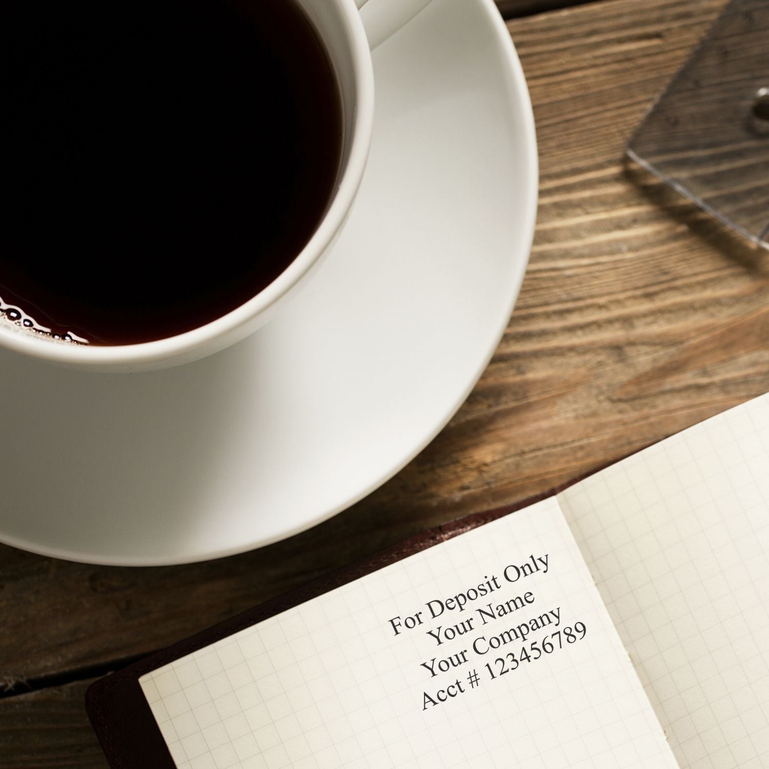 A 4 Line Regular Rubber Check Endorsement Stamp imprint on a notebook next to a cup of coffee on a wooden table.