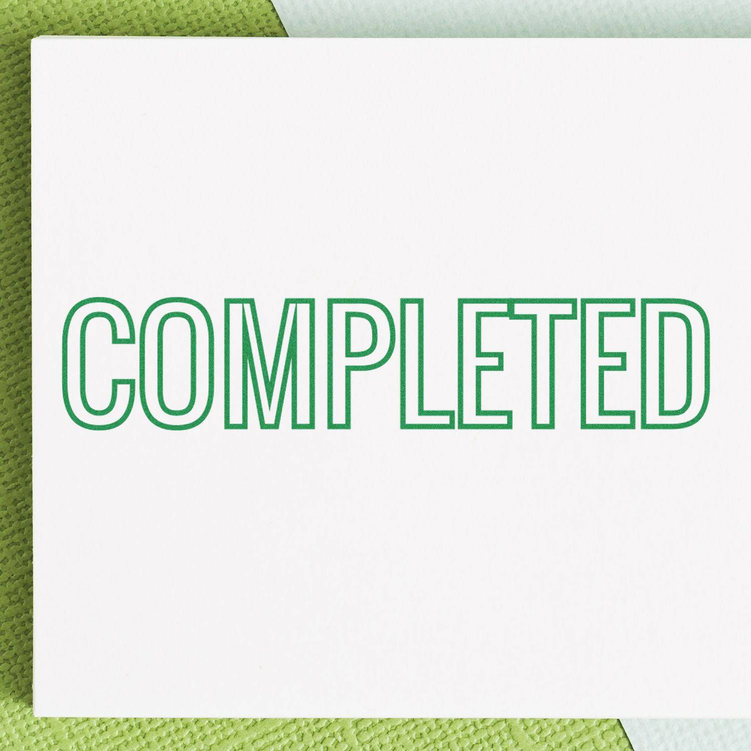 Large Pre-Inked Outline Completed Stamp in green ink on white paper, placed on a textured green and white background.