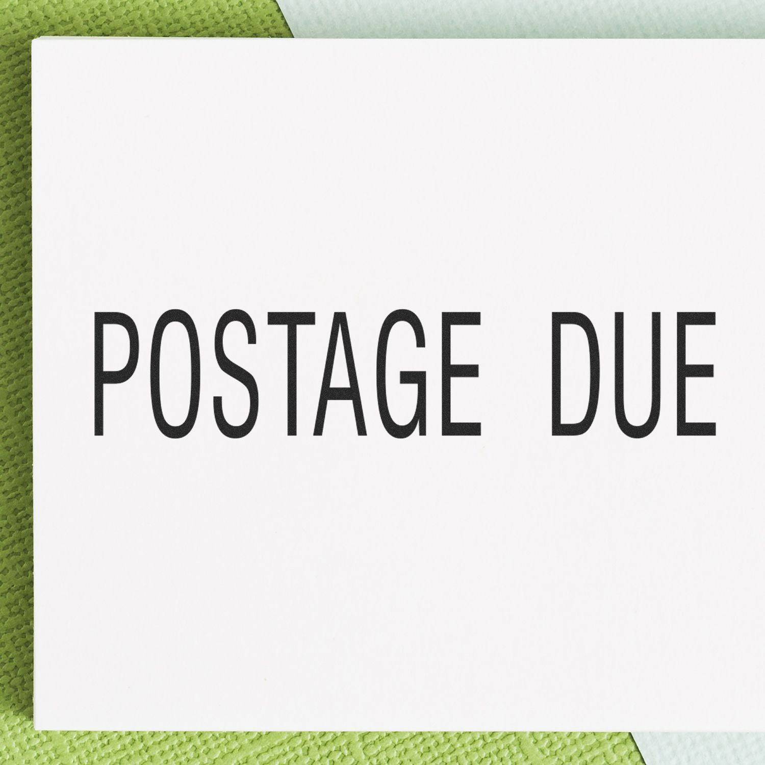 Large Pre-Inked Postage Due Stamp with bold black text on a white background, placed on a green textured surface.