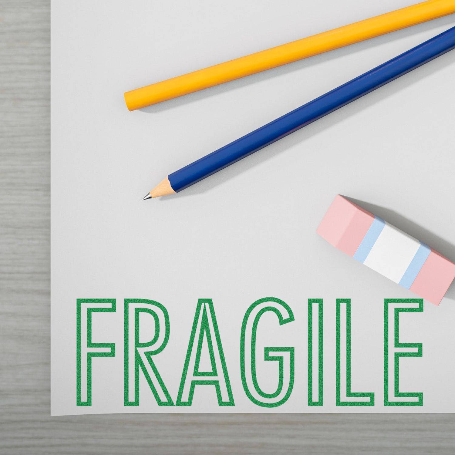 Large Pre-Inked Fragile Stamp on a white surface with two pencils and an eraser nearby.