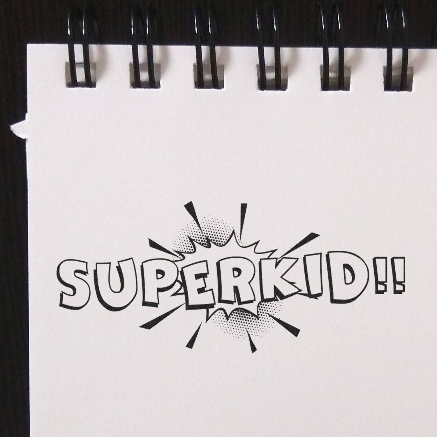 A notebook with a stamped SUPERKID!! design using the Large Pre-Inked Superkid Stamp, featuring bold, comic-style text and a burst effect.