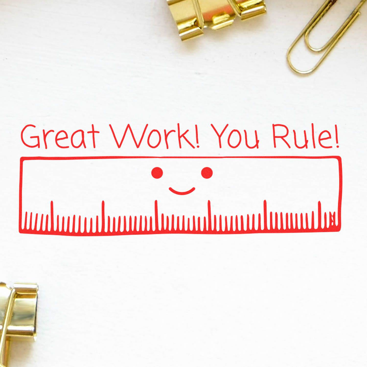 Large Pre-Inked Great Work You Rule Stamp with a smiling ruler and the text Great Work! You Rule! in red ink, surrounded by paper clips.