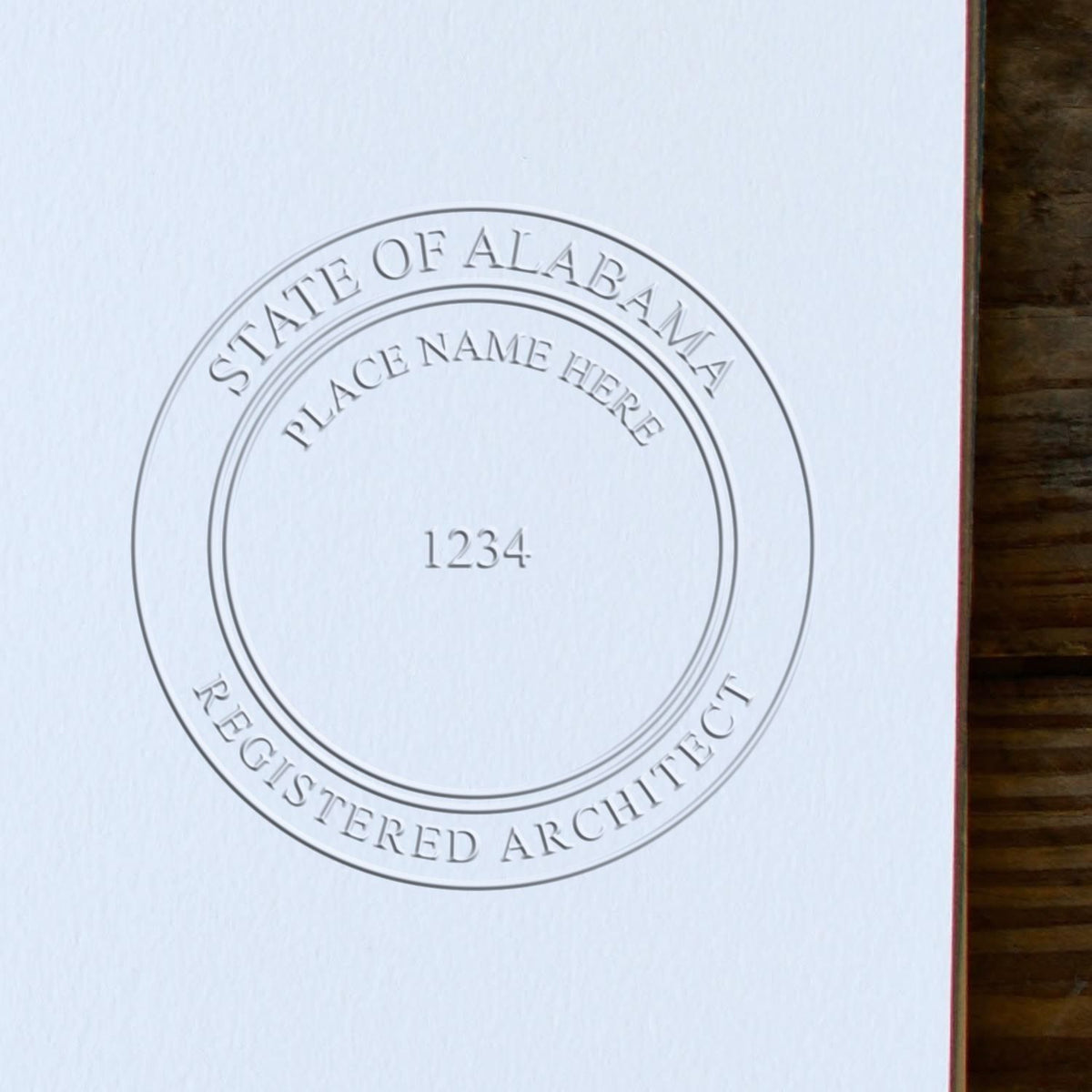 A lifestyle photo showing a stamped image of the Alabama Desk Architect Embossing Seal on a piece of paper