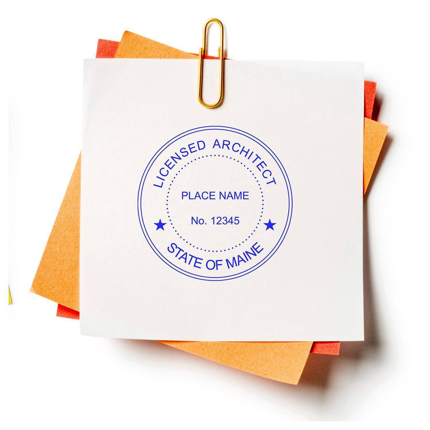 Architect Regular Rubber Stamp of Seal in use, displaying a circular design with 'Licensed Architect' and 'State of Maine' text, along with placeholders for name and number, stamped on a white paper clipped to colored sheets.