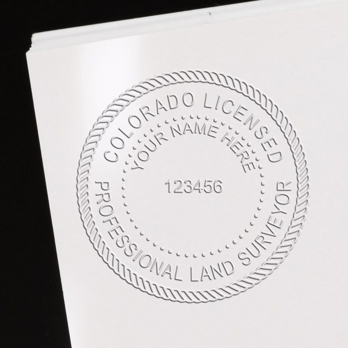 An in use photo of the Hybrid Colorado Land Surveyor Seal showing a sample imprint on a cardstock