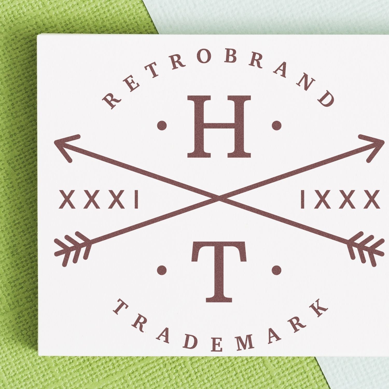 Custom Rubber Stamp Size 7 Inch Diameter imprinting a stylish design with arrows and text on a white card, placed on a green textured surface.
