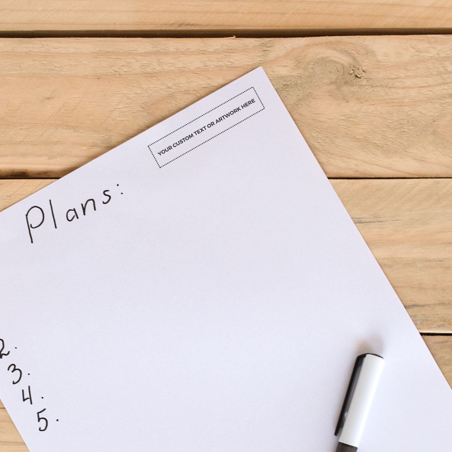 A Custom Self Inking Stamp Trodat 4918 Size 5/8 x 3 is shown on a wooden table next to a paper with handwritten plans and a marker.