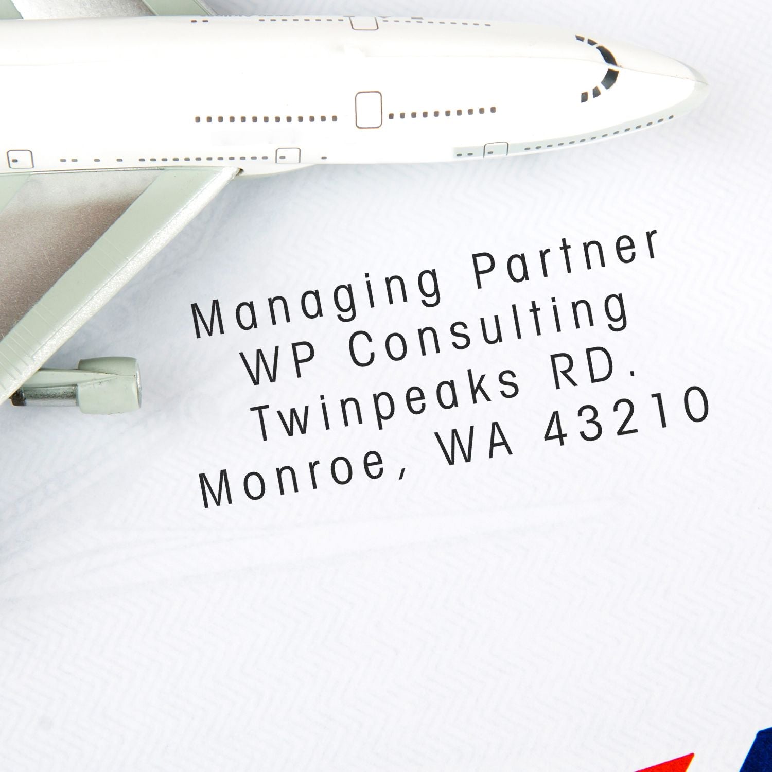 MaxLight XL2-42 Custom Pre-Inked Business Stamp 11/16 x 1-15/16 imprinting an address on paper next to a model airplane.
