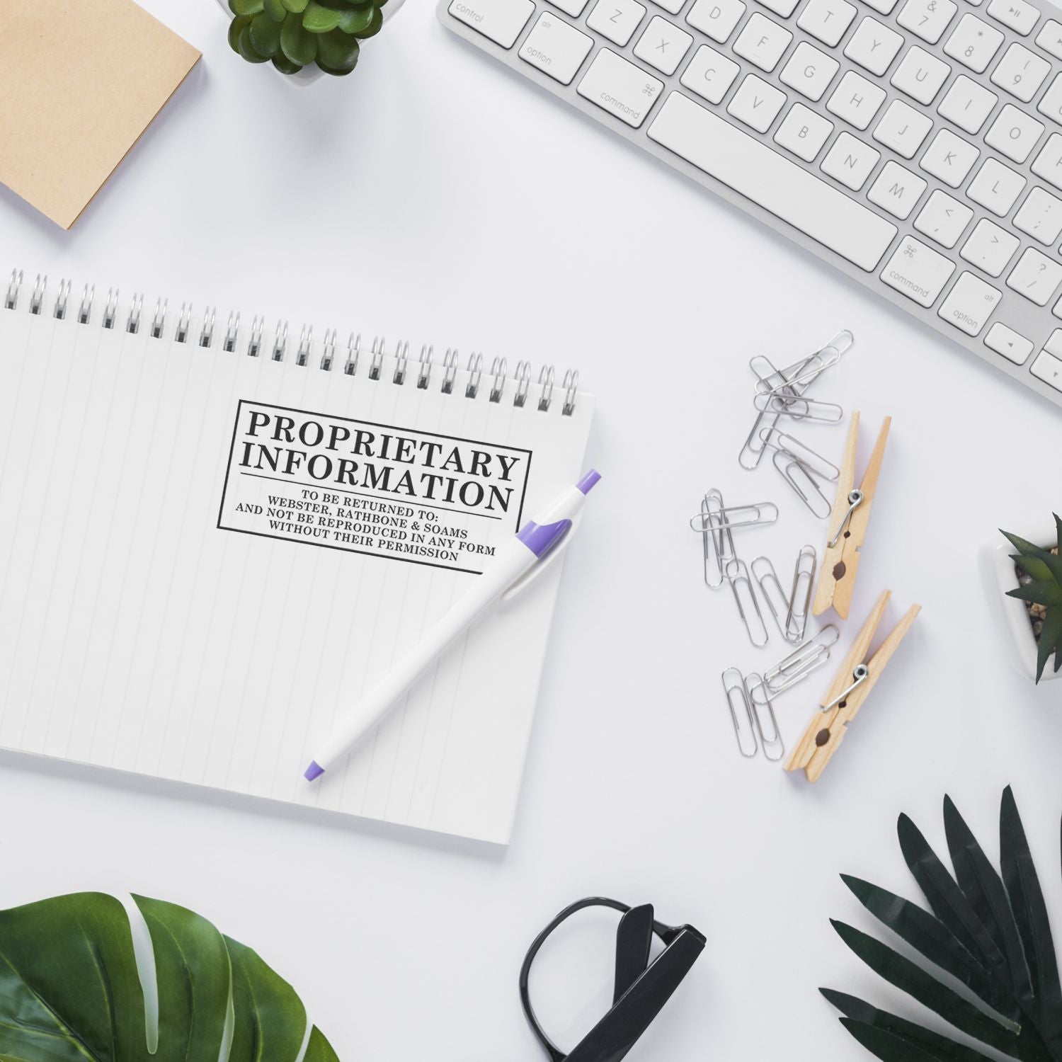 Custom Self Inking Stamp Trodat 4931 Size 1-1/8 x 2-3/4 used on a notebook, surrounded by office supplies, plants, and a keyboard.