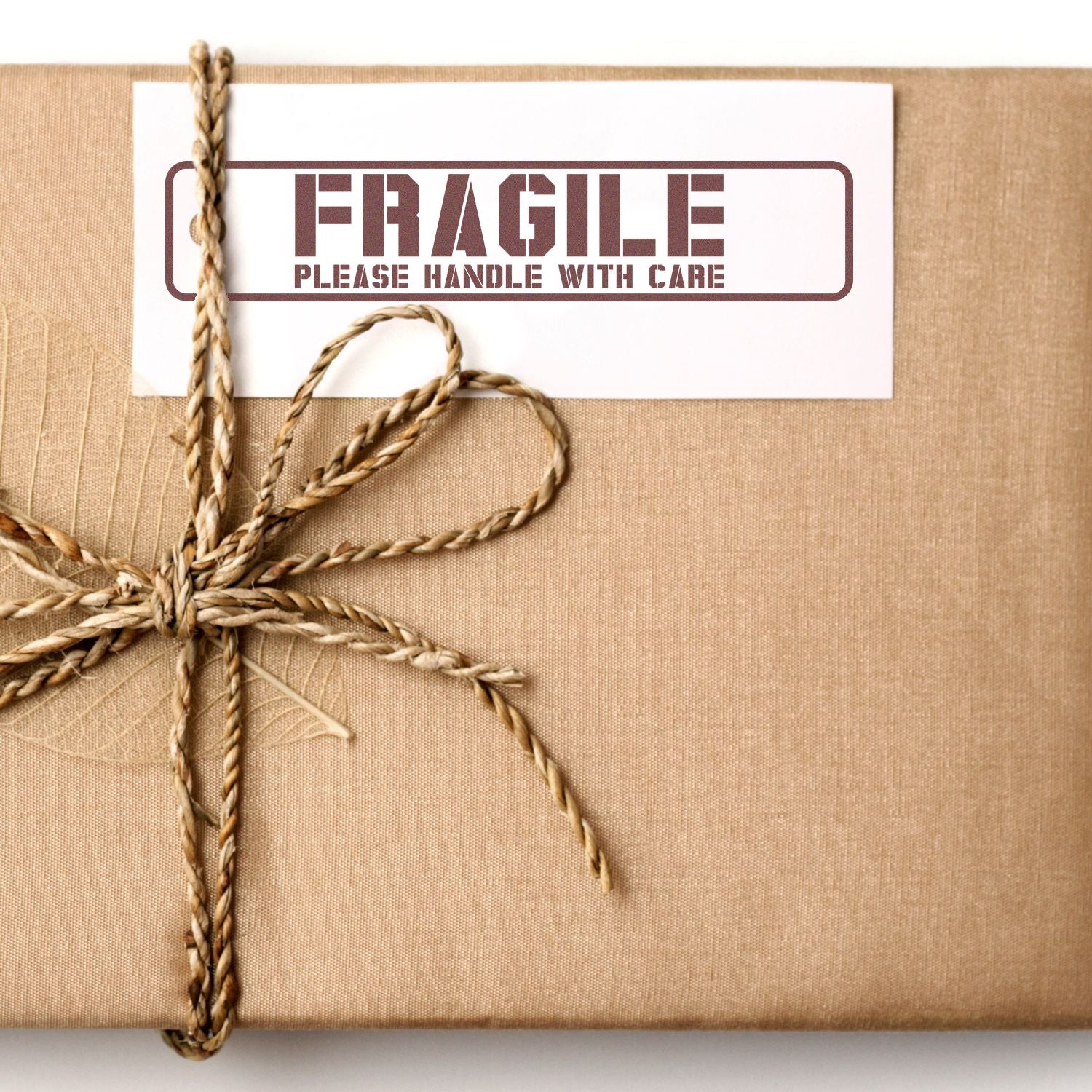 A brown package with a Fragile, Please Handle With Care label stamped using the MaxLight XL2-720 Custom Pre-Inked Business Stamp 1 x 4.