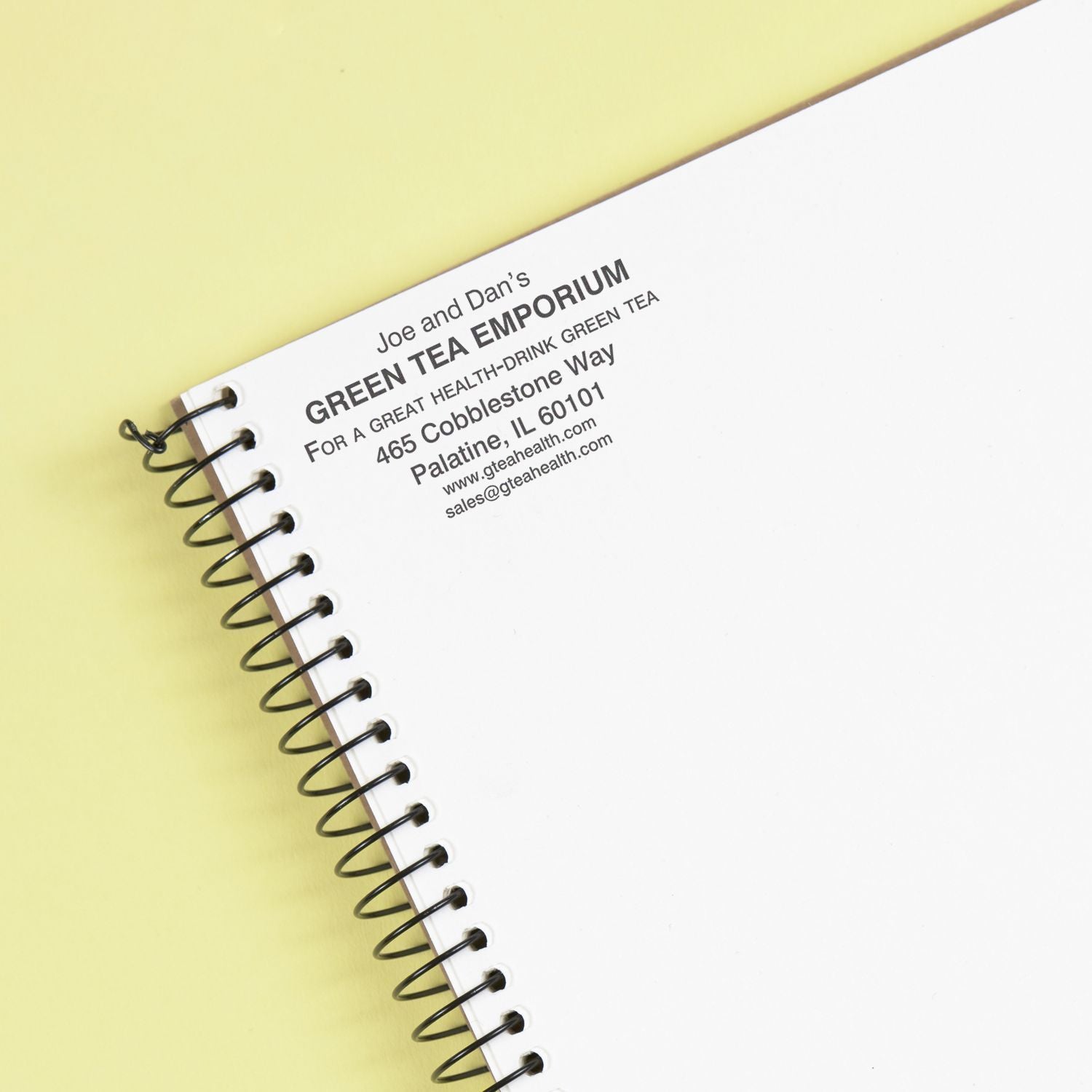 MaxLight XL2-225 Custom Pre-Inked Business Stamp 2 x 3 used on a spiral notebook, displaying business information in black ink.