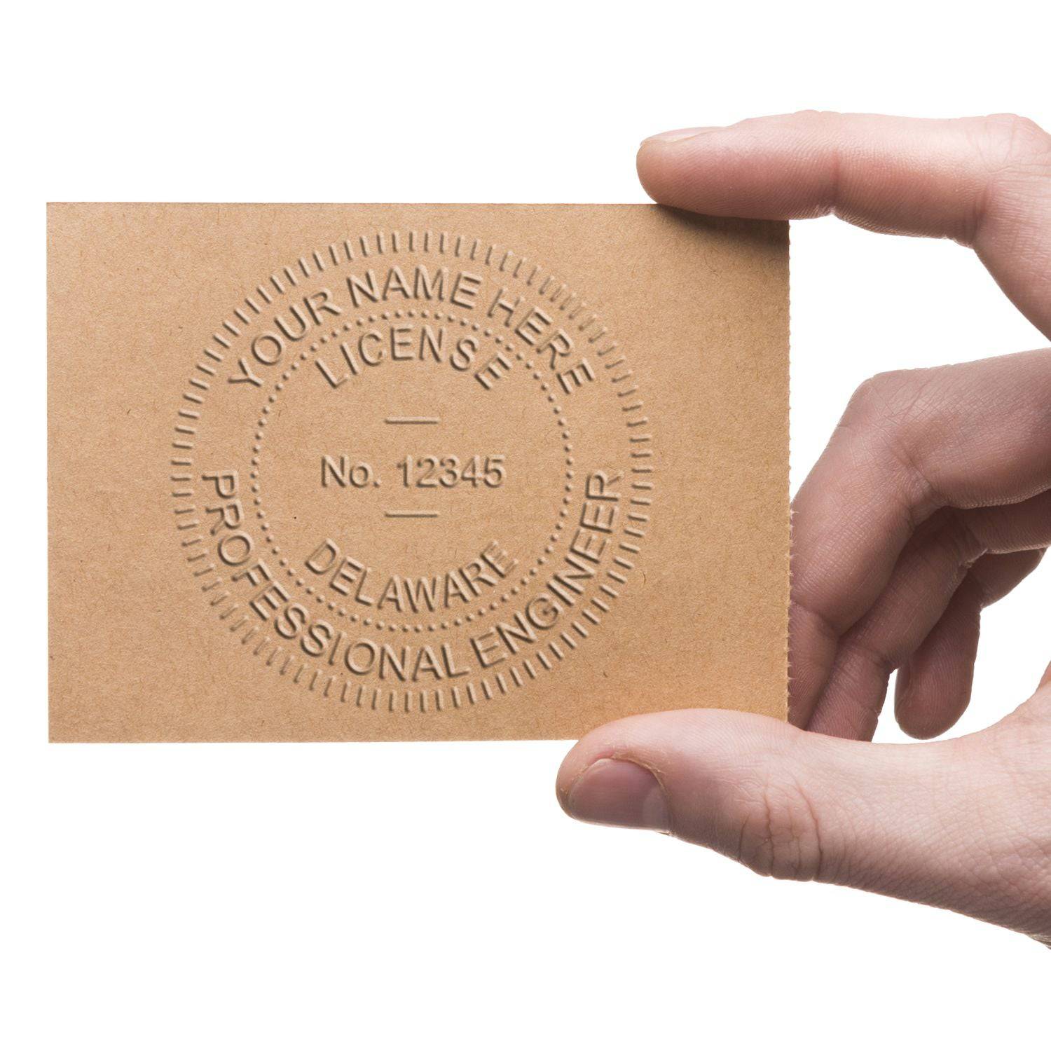 A hand holding a brown card embossed with a circular seal that reads YOUR NAME HERE, LICENSE No. 12345, DELAWARE, PROFESSIONAL ENGINEER using the Professional Engineer Blue Soft Seal Embosser.