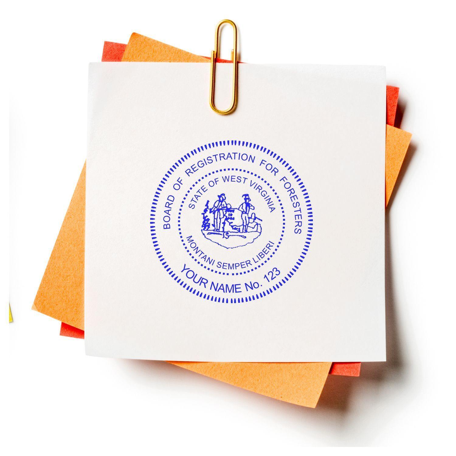 Forester Self Inking Rubber Stamp of Seal in blue ink on white paper, clipped with a gold paperclip to orange and red papers.