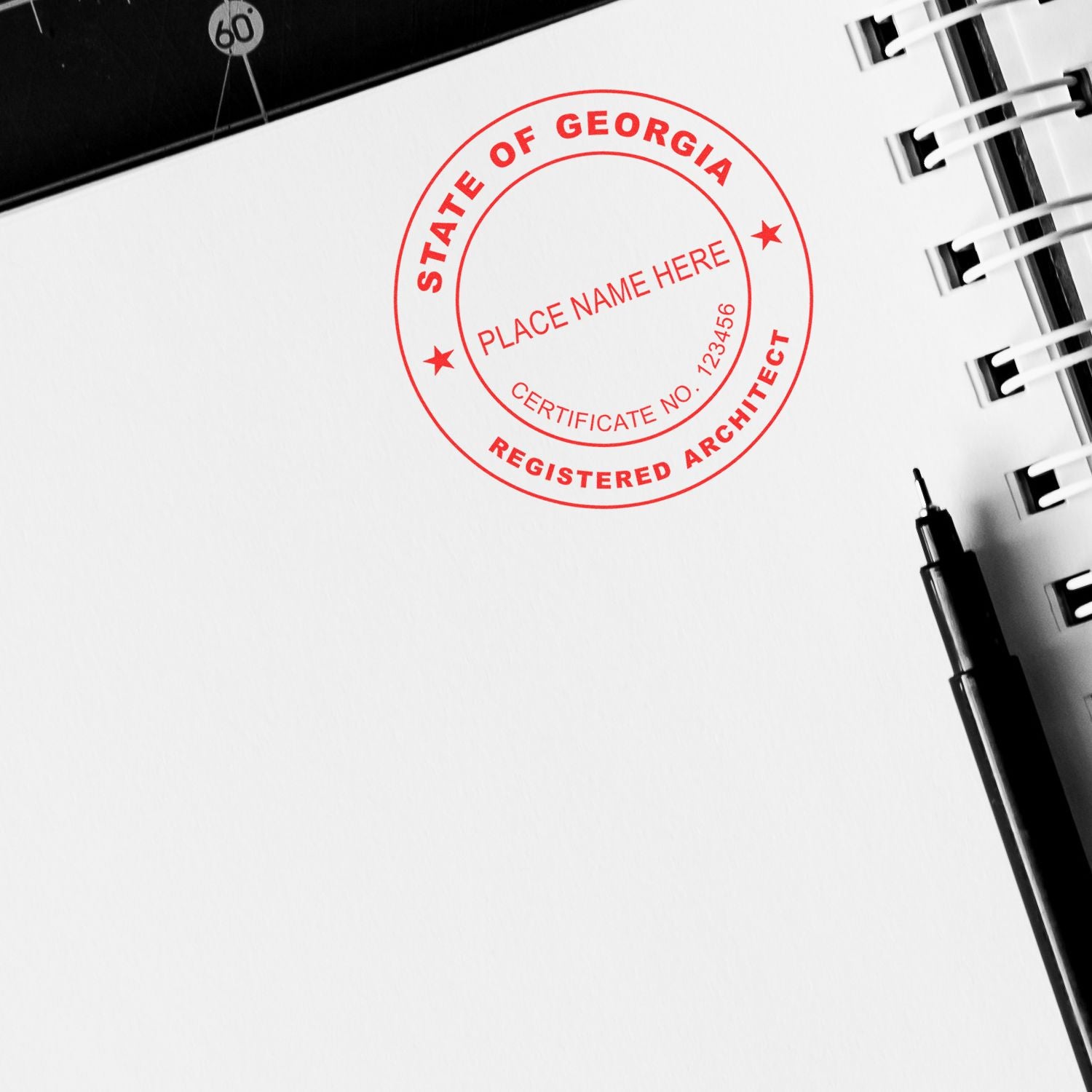 Self Inking Georgia Architect Stamp in red ink on white paper next to a black pen and a spiral notebook.