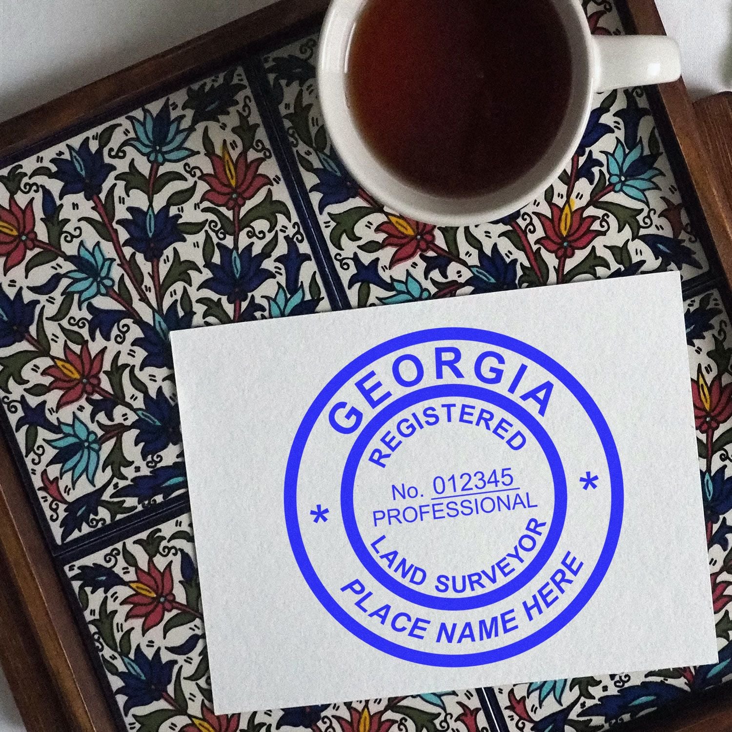 Georgia Land Surveyor Seal Stamp, GA PLS Stamp on a decorative tile tray with a cup of tea.