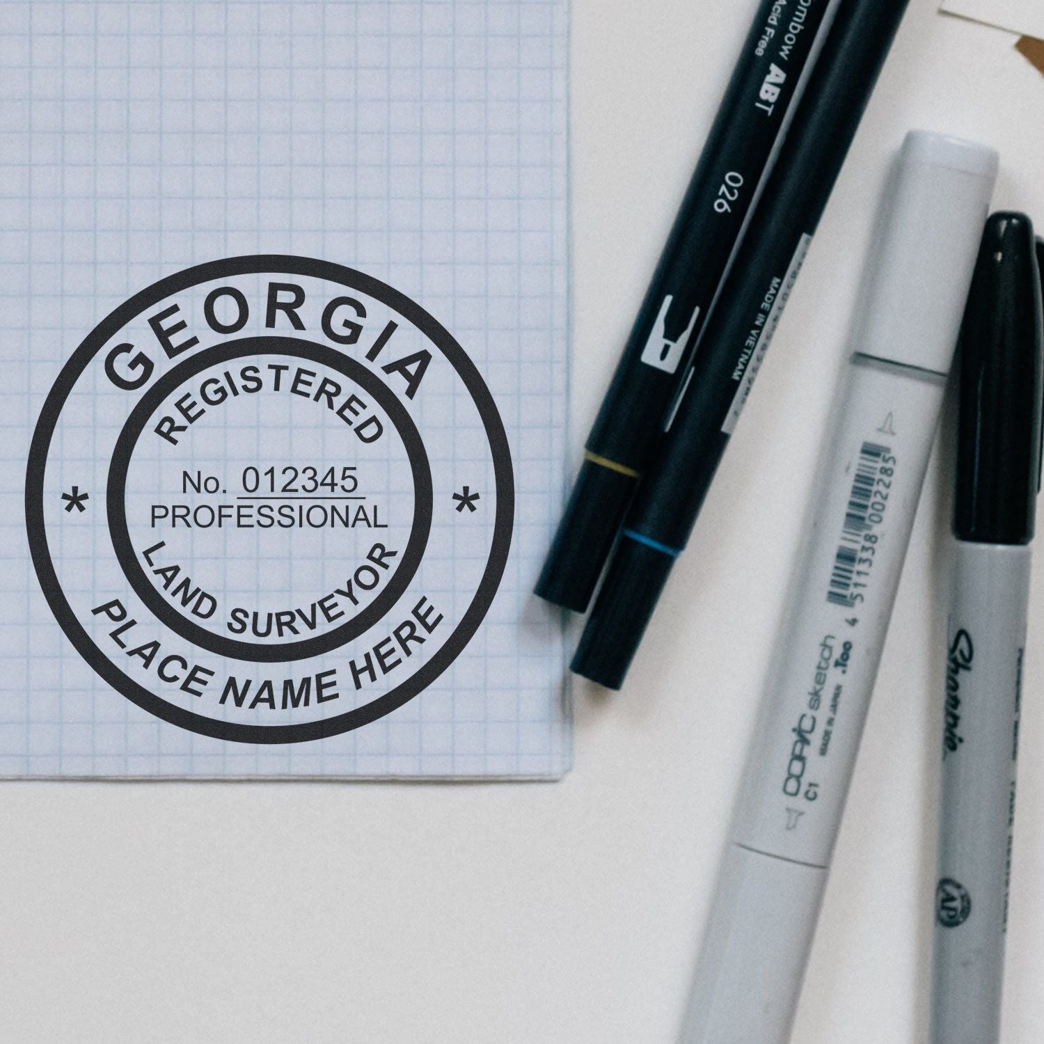Premium MaxLight Pre-Inked Georgia Surveyors Stamp on graph paper with pens and markers nearby.