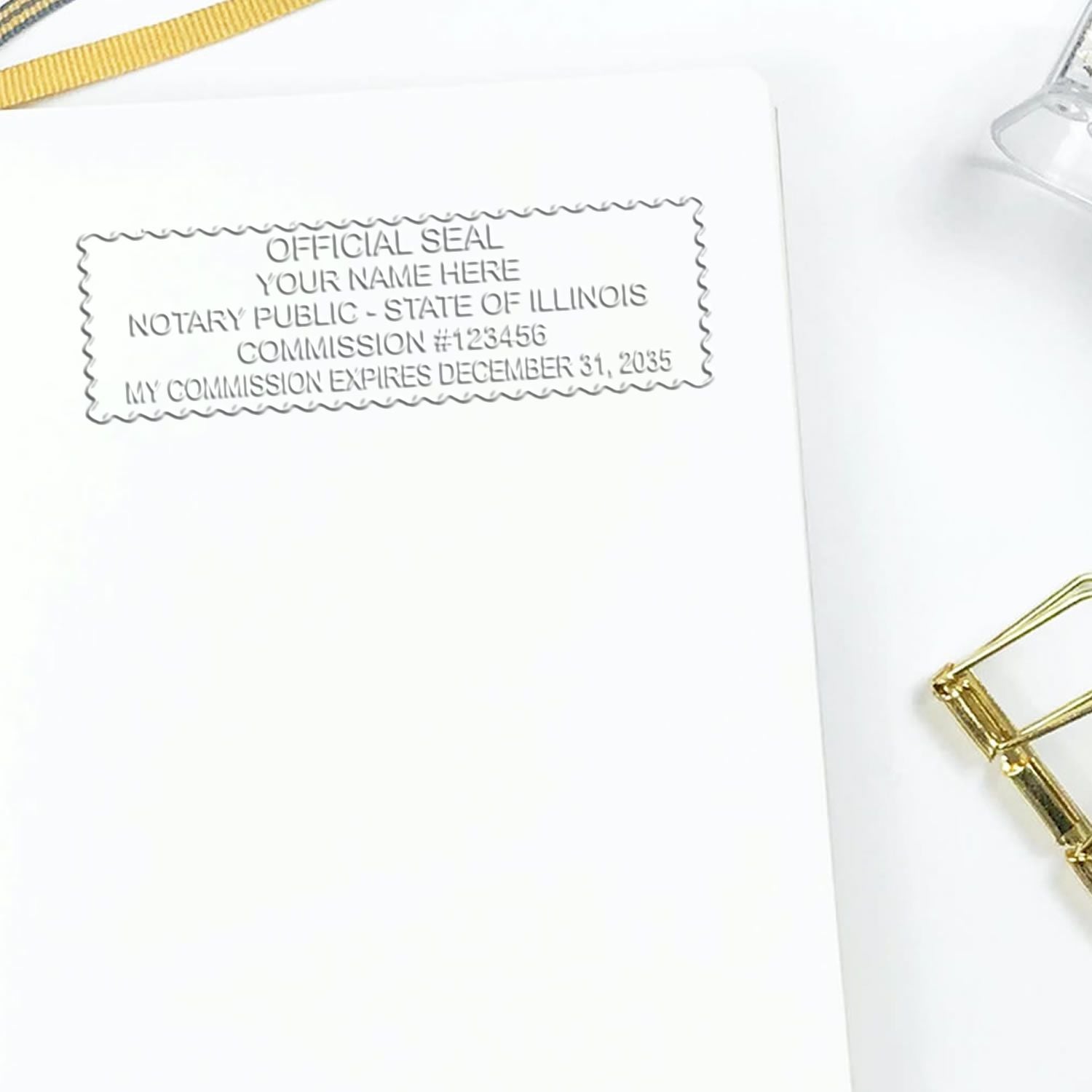 A lifestyle photo showing a stamped image of the Illinois Handheld Notary Seal Embosser on a piece of paper