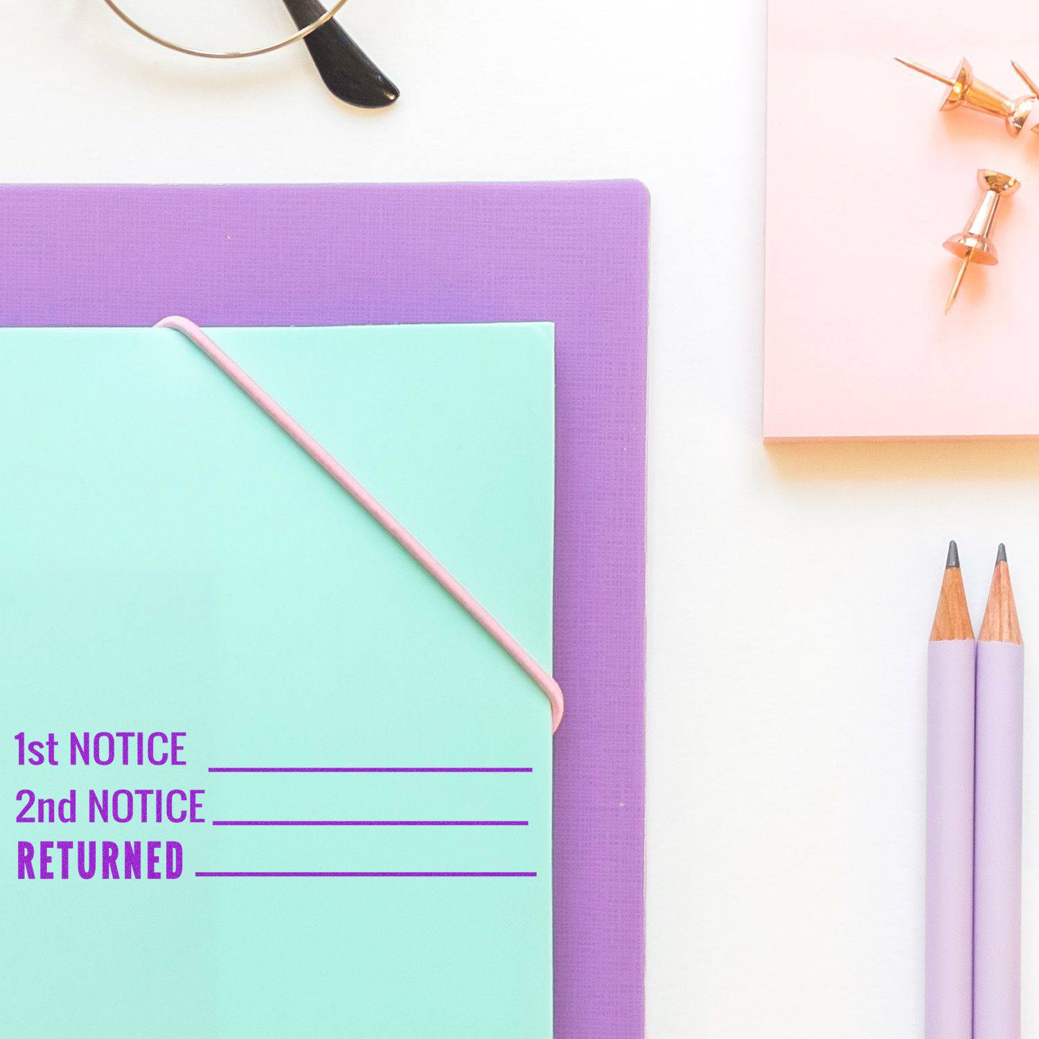 Large Pre-Inked 1st 2nd Notice Returned Stamp on a turquoise folder with a purple background, pencils, and push pins nearby.