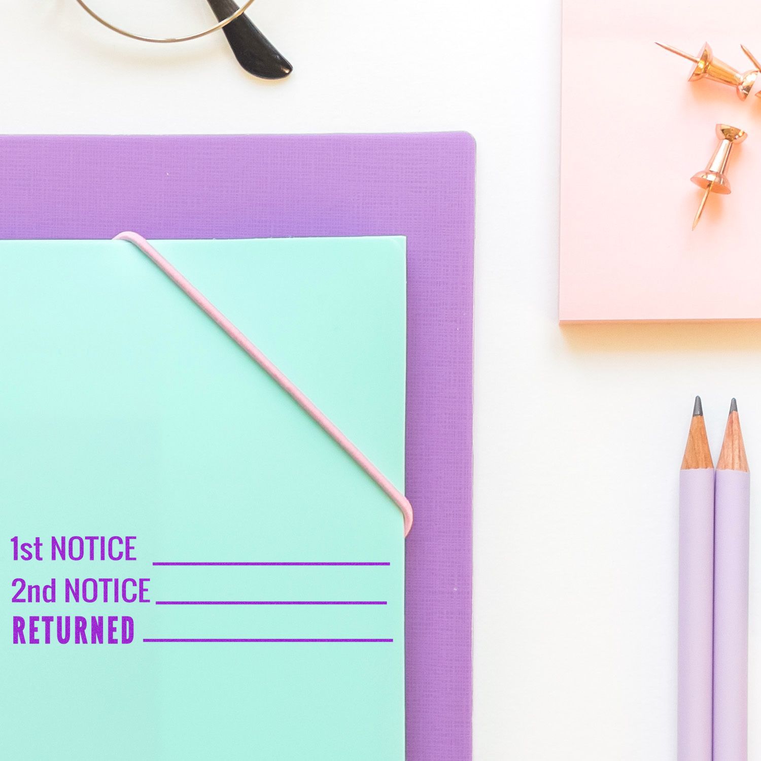 Slim Pre-Inked 1st 2nd Notice Returned Stamp on a pastel green folder with purple and pink stationery items nearby.