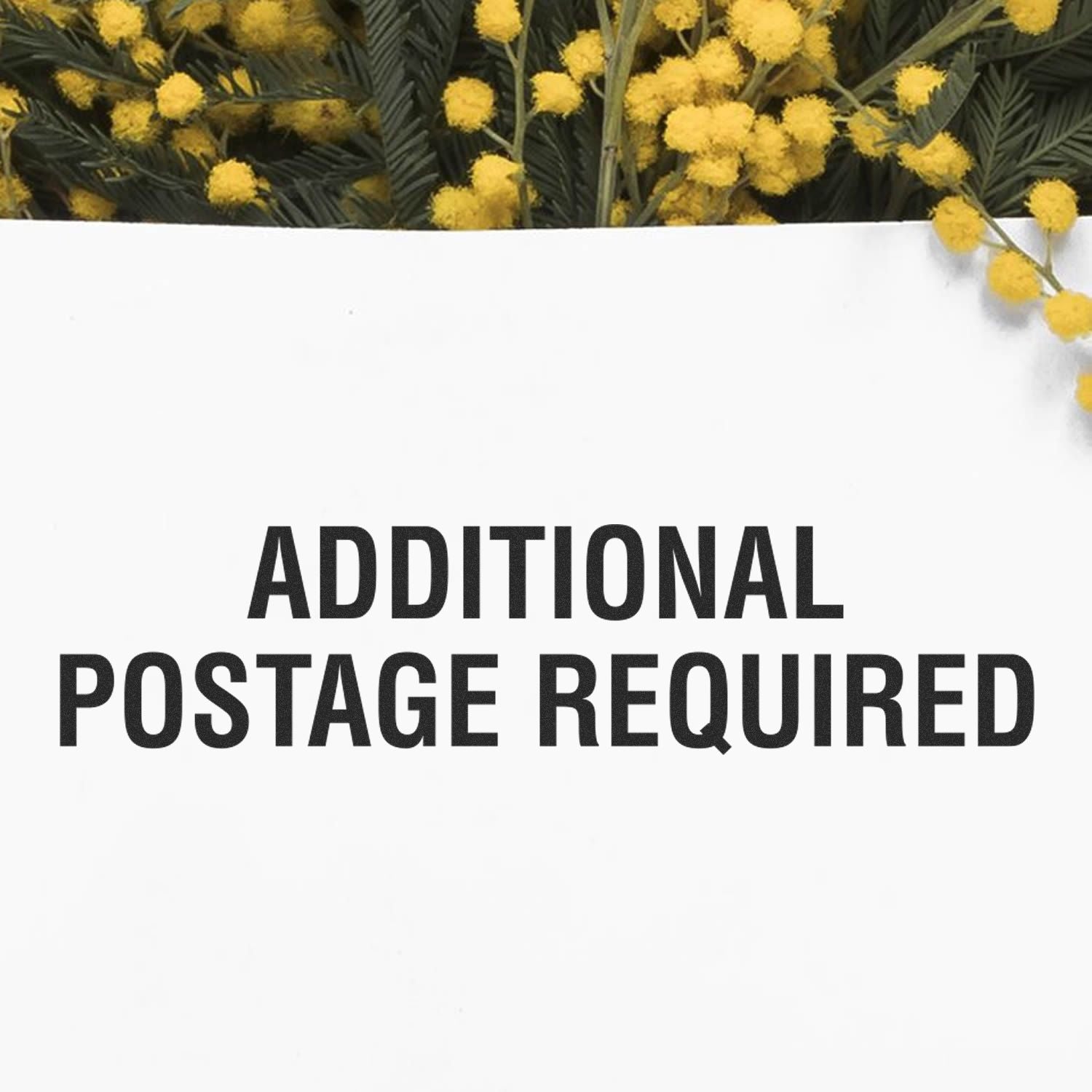 Slim Pre-Inked Additional Postage Required Stamp on white paper with yellow flowers in the background.
