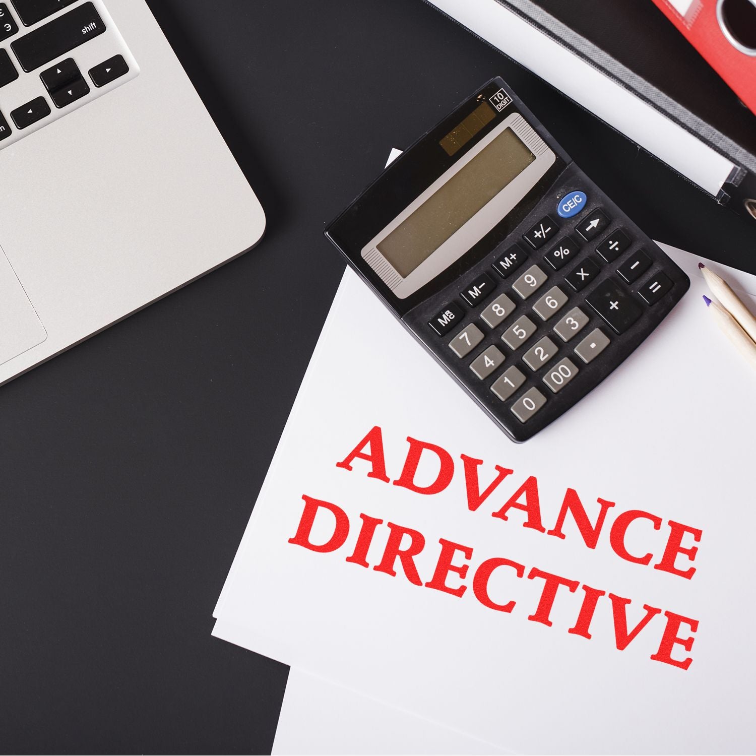 Advance Directive rubber stamp on documents next to a calculator, pencil, and laptop on a black desk.