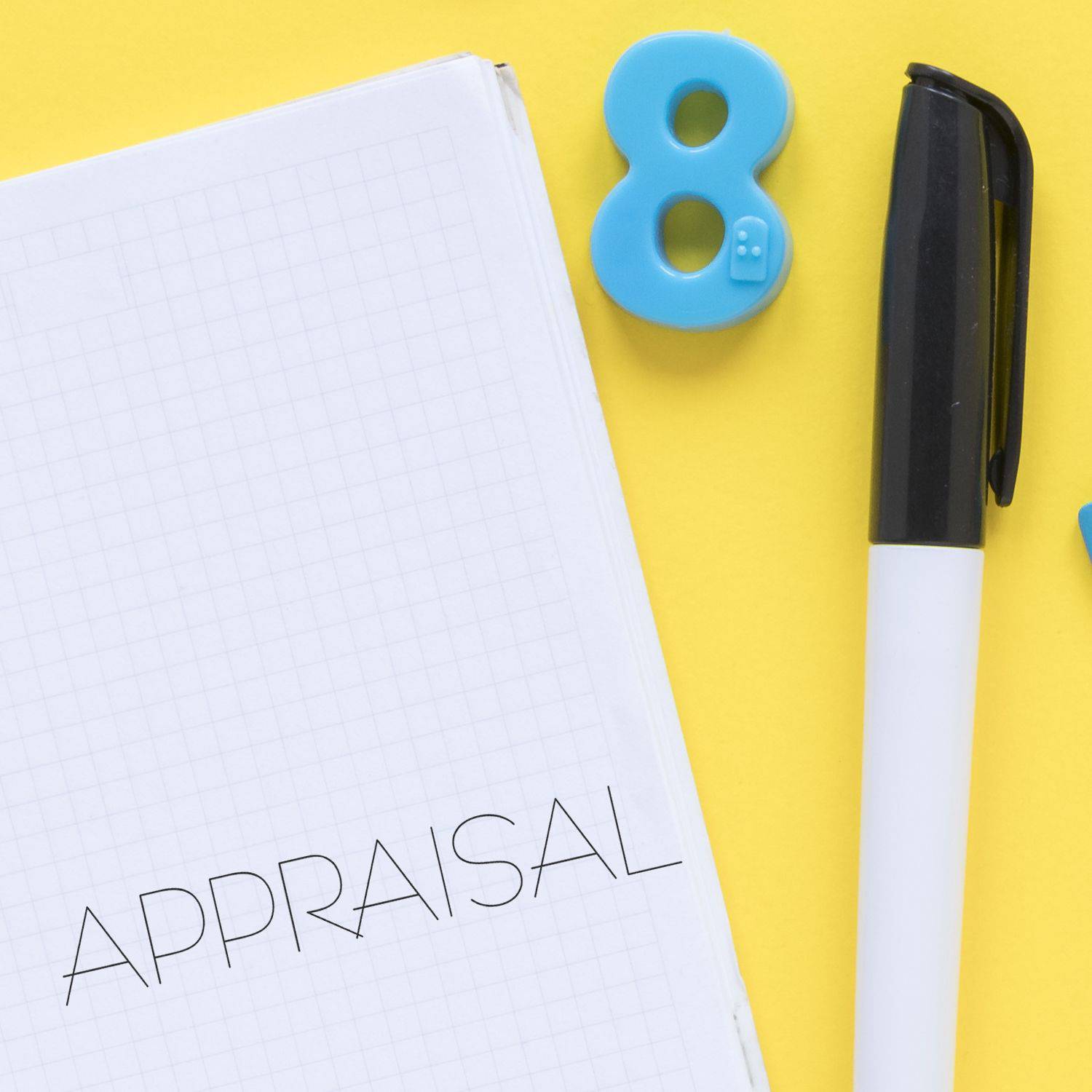 Large Pre-Inked Appraisal Stamp in use on a notebook with APPRAISAL text, alongside a pen and a blue number 8 on a yellow background.