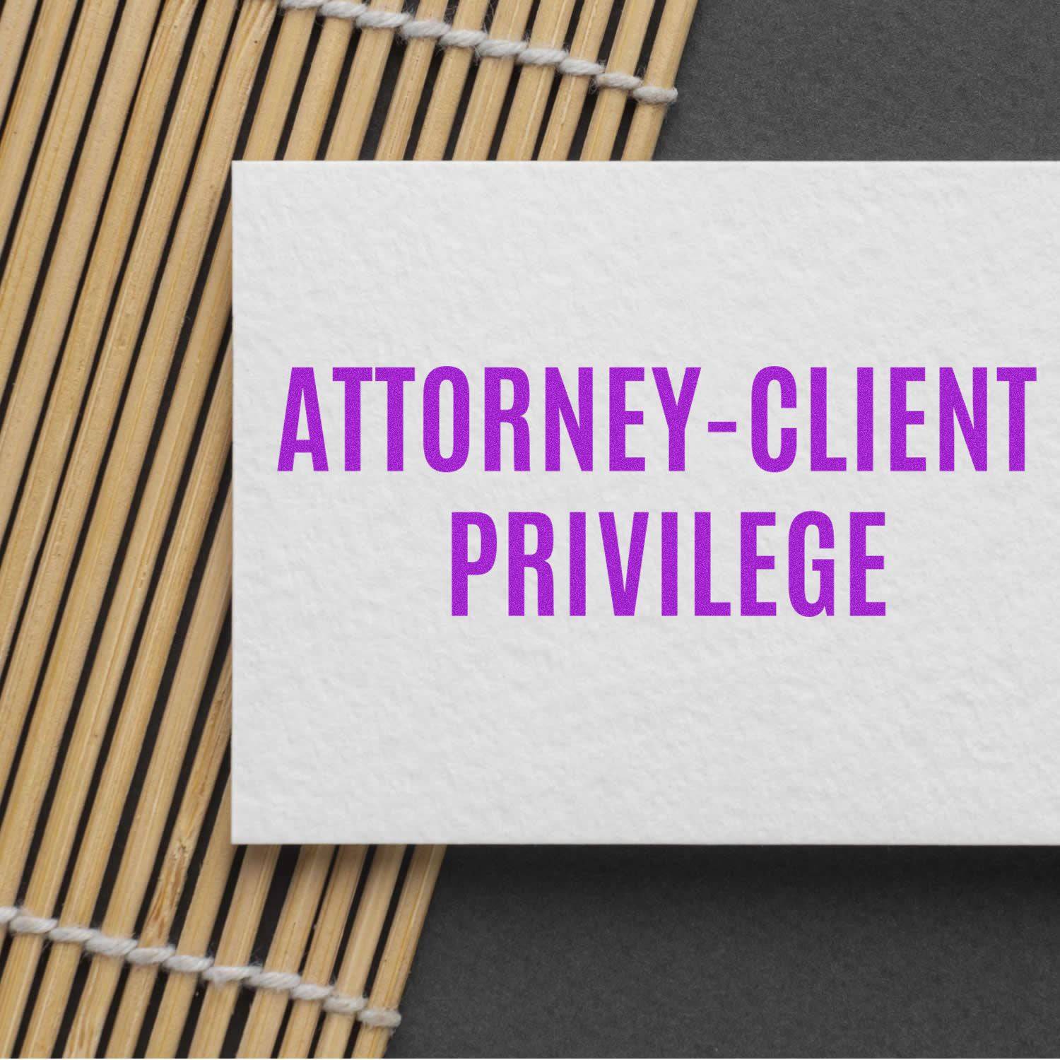 Large Self Inking Attorney-Client Privilege Stamp used on a white card with purple text, placed on a bamboo mat background.