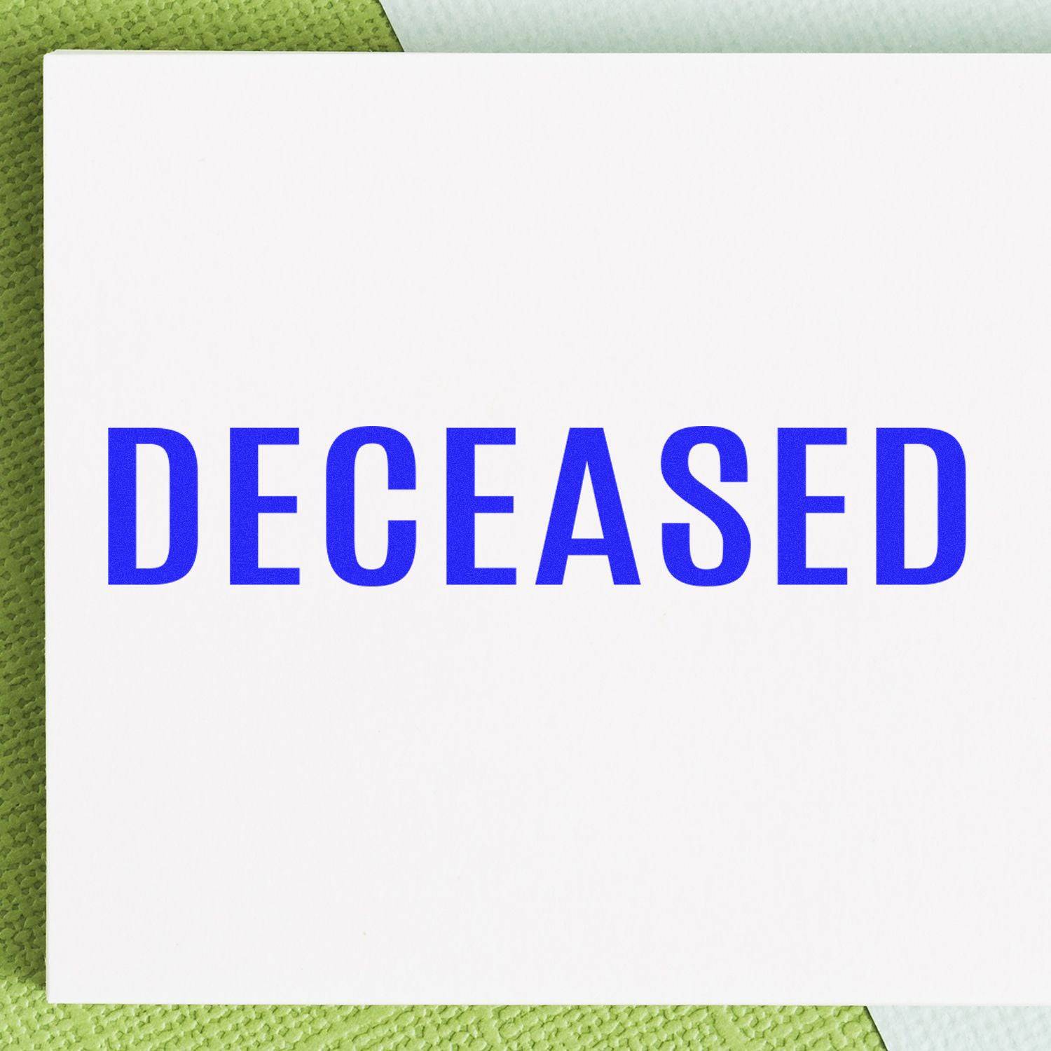 Large Pre-Inked Bold Deceased Stamp imprint in blue ink on white paper, placed on a textured green and white background.