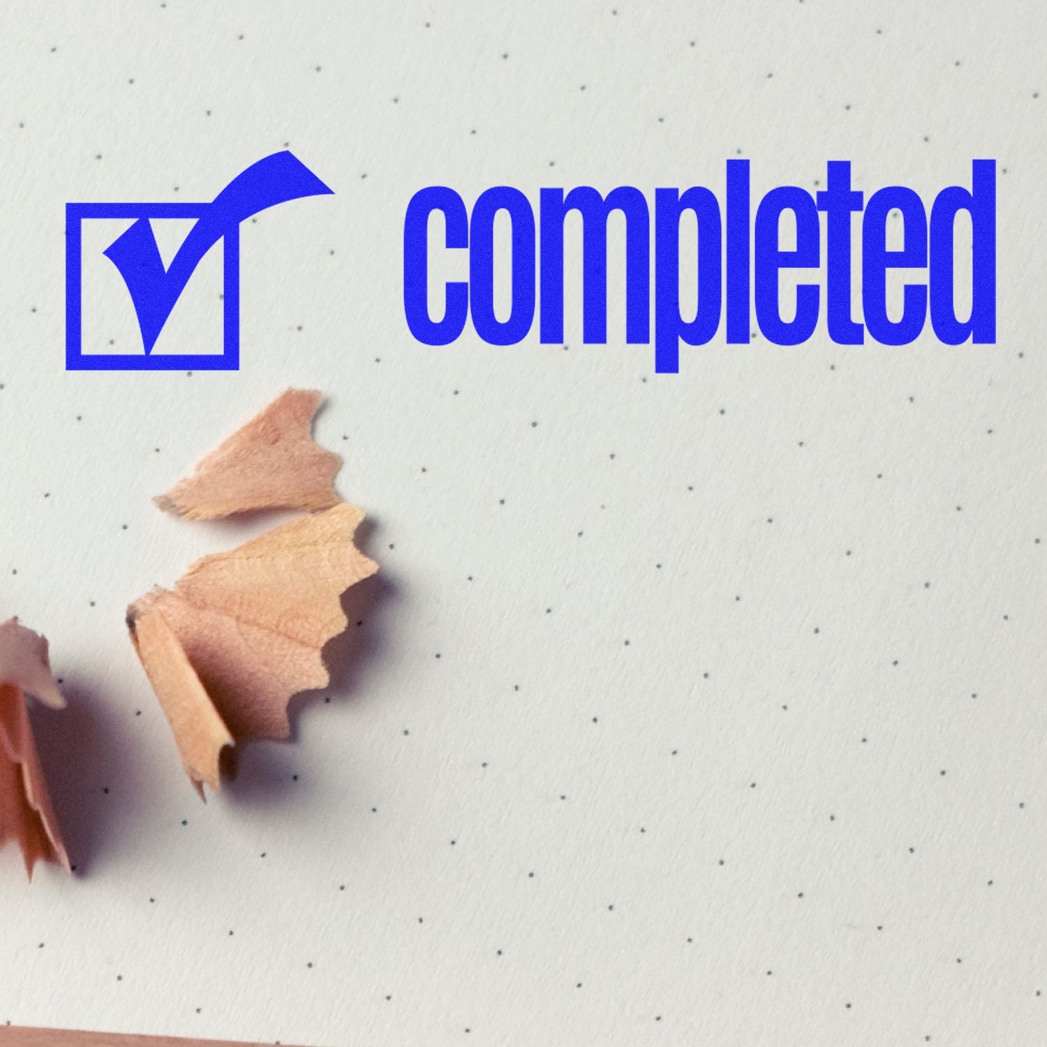 Slim Pre-Inked Completed with Checkbox Stamp on dotted paper with pencil shavings nearby.