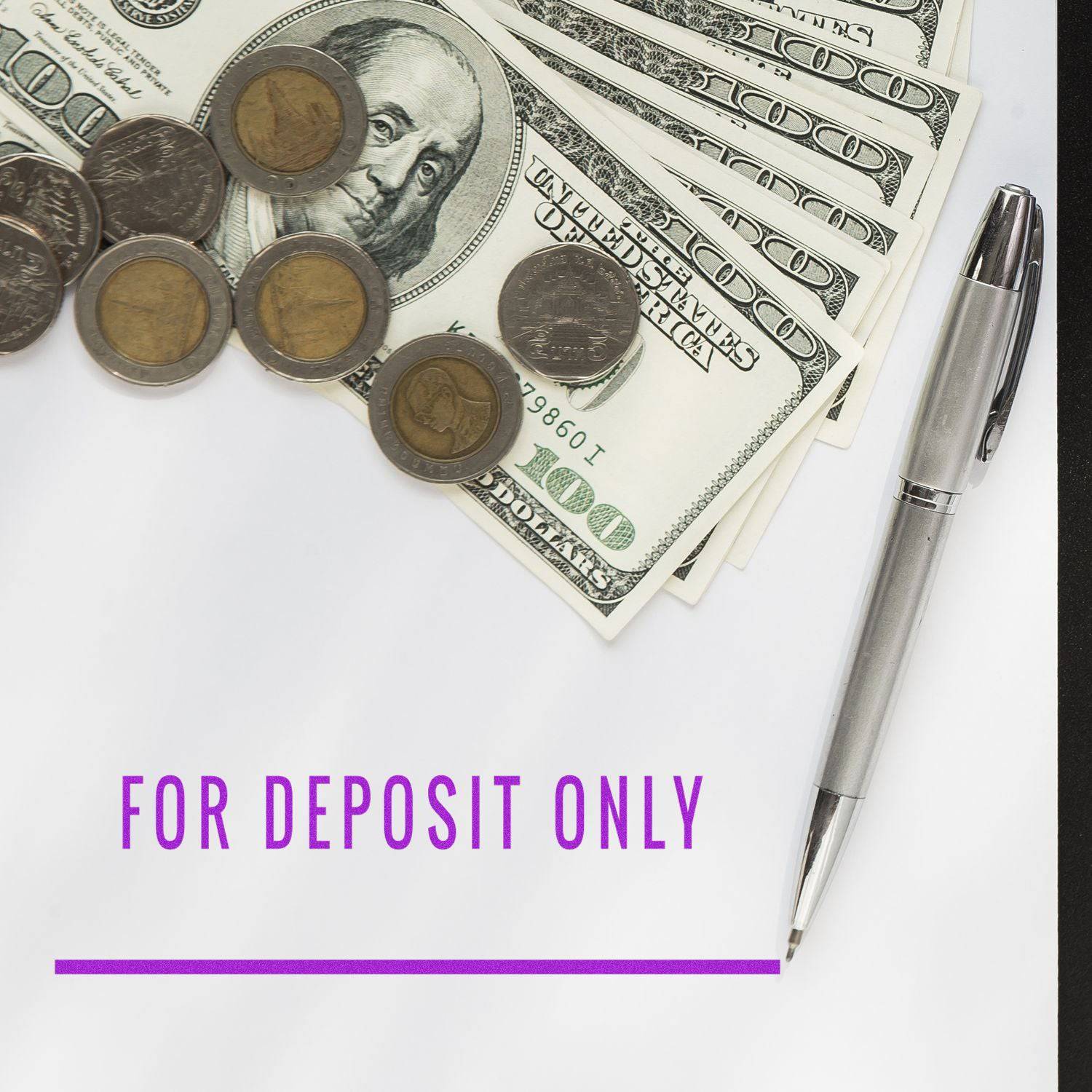 Large Pre-Inked For Deposit Only with Line Stamp in use, with a pen, coins, and dollar bills on a white surface.