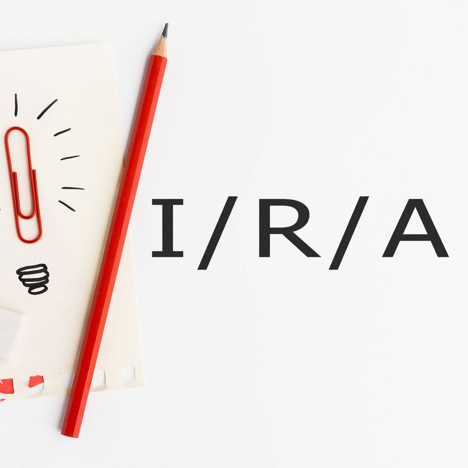 Large Pre-Inked I/R/A Stamp in use, with a red pencil and paperclip on a notepad, showcasing the clear and bold stamped text I/R/A .