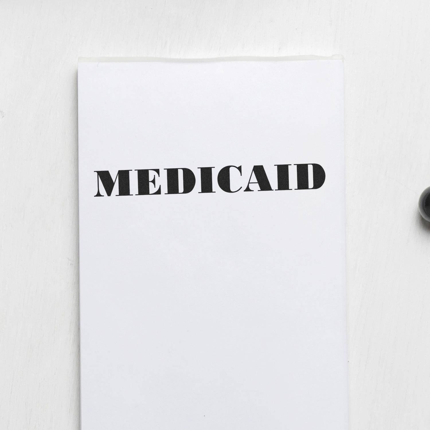 Large Pre-Inked Medicaid Stamp in use, displaying the word 'MEDICAID' clearly stamped on a white sheet of paper.