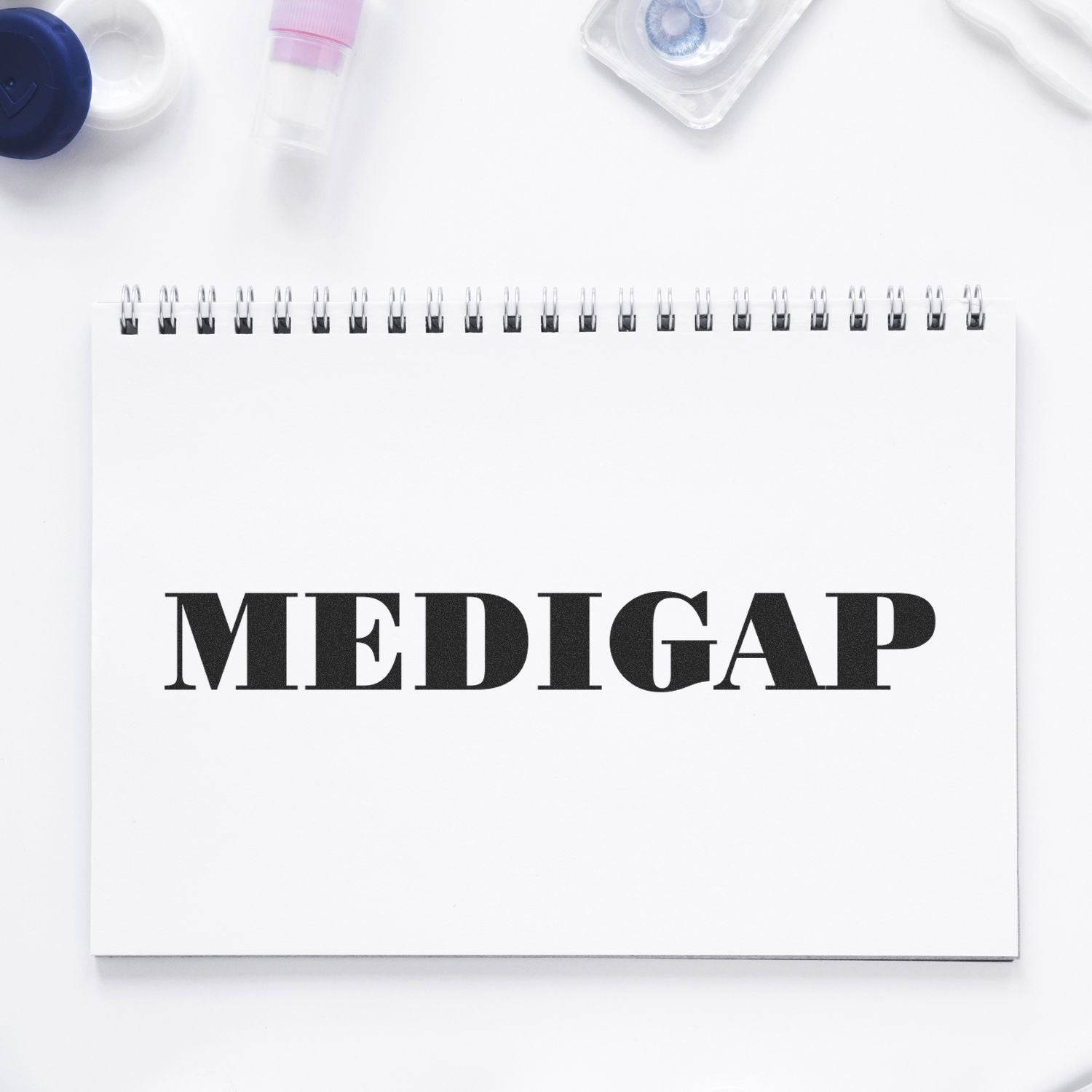 Large Pre-Inked Medigap Stamp in use, displaying the word MEDIGAP on a white spiral notebook, surrounded by office supplies.