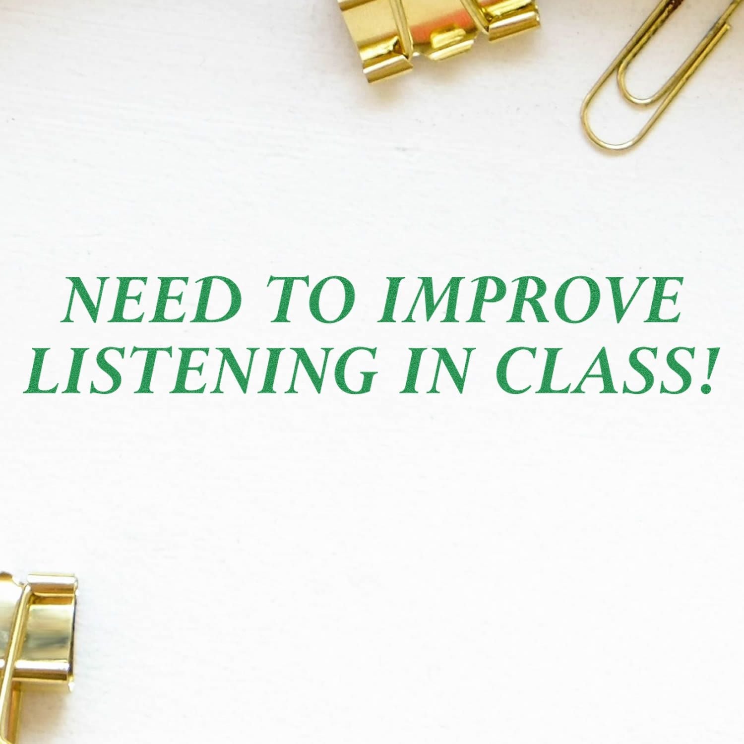 Self Inking Need To Improve Listening Stamp in use, displaying NEED TO IMPROVE LISTENING IN CLASS! text on white paper with gold clips nearby.