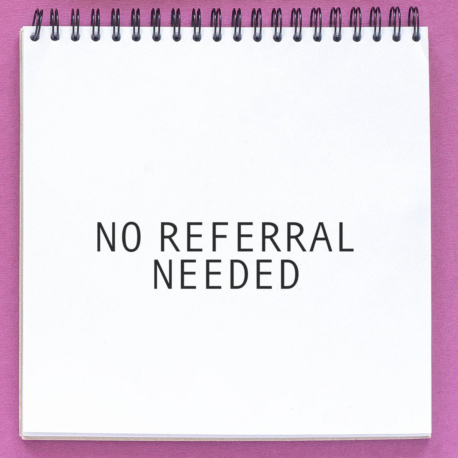 Large Pre-Inked No Referral Needed Stamp imprint on a white notepad with a pink background.