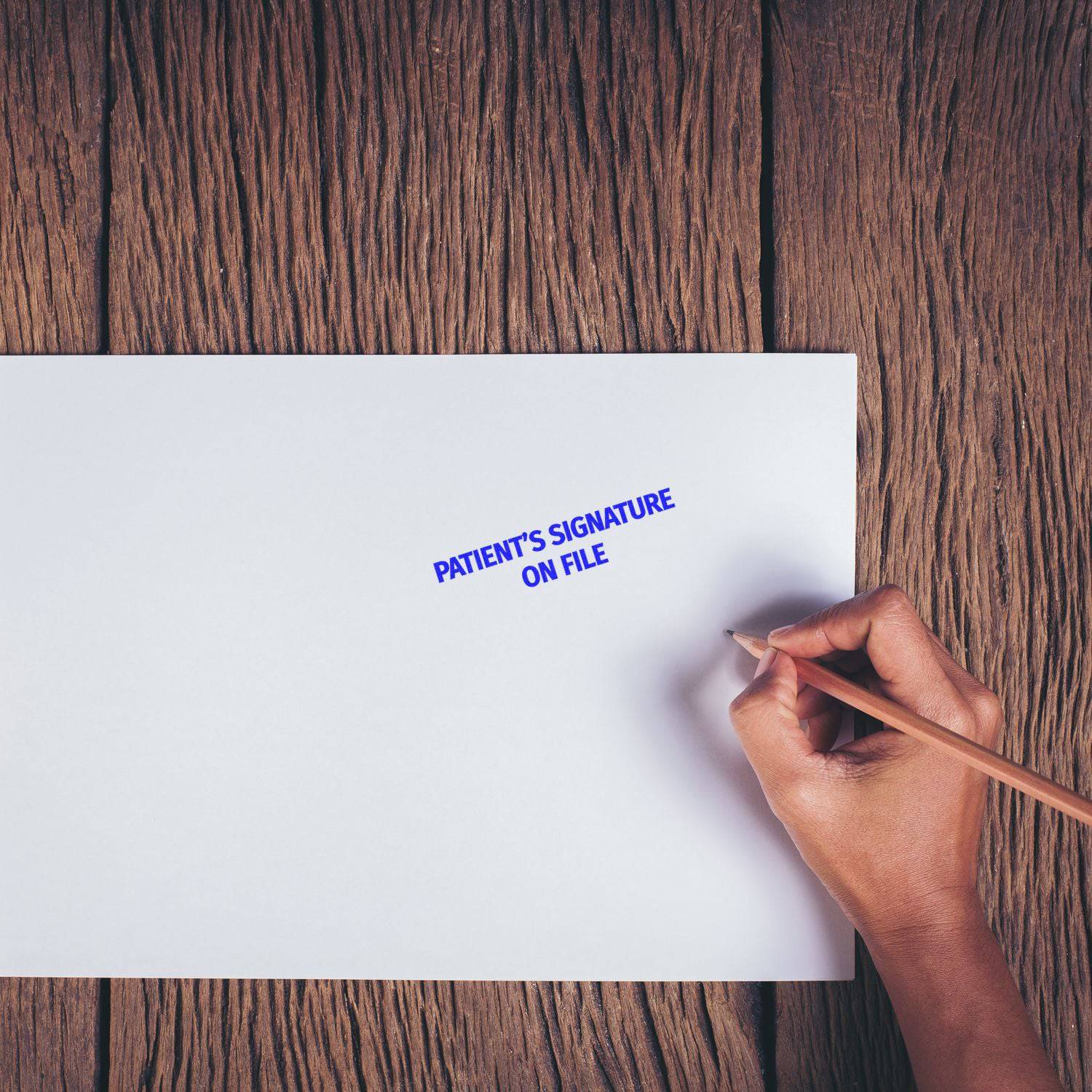 Hand holding a pencil next to a stamped PATIENT'S SIGNATURE ON FILE on white paper using the Large Patient's Signature on File Rubber Stamp.