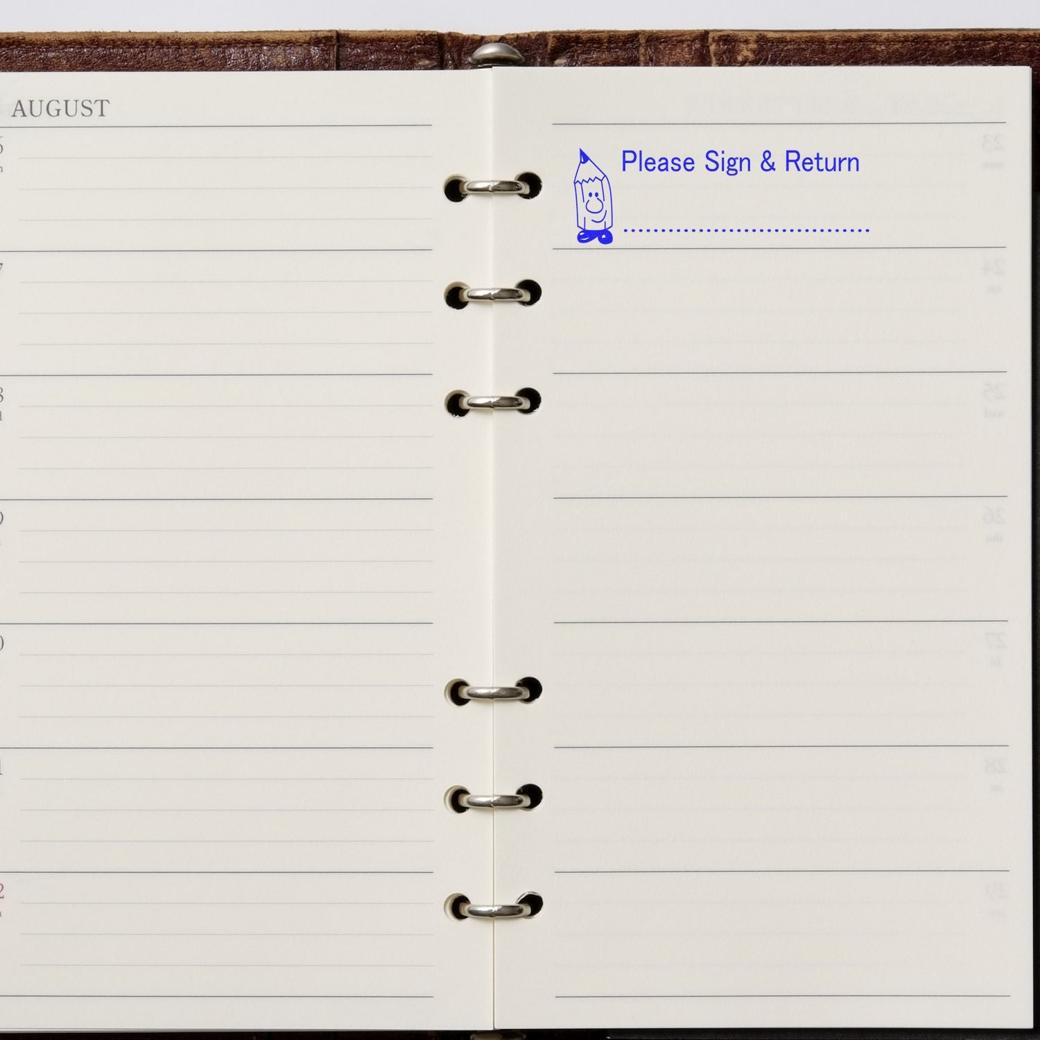 Open planner with a Please Sign and Return Rubber Stamp imprint in blue ink on the top right page.
