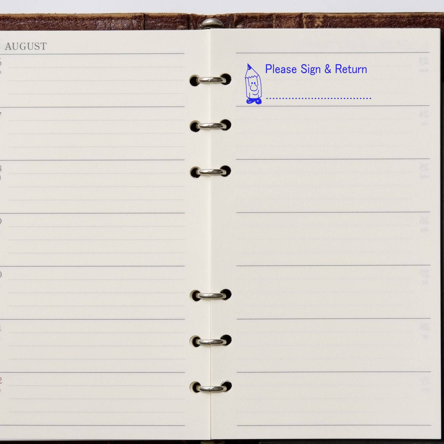 Open planner with a stamped message Please Sign and Return in blue ink using the Large Please Sign and Return Rubber Stamp.