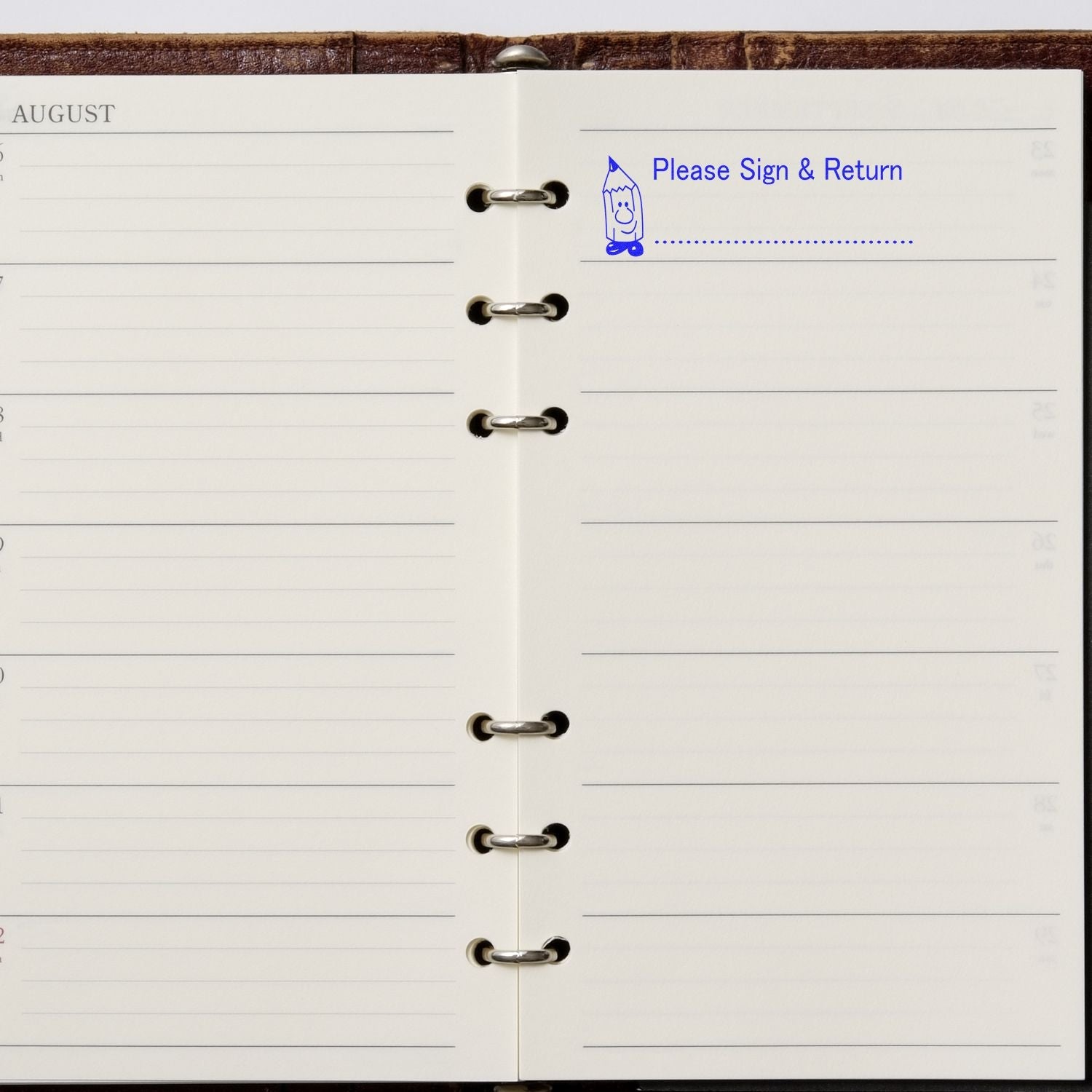 Open planner with a stamped message Please Sign and Return in blue ink using the Self Inking Please Sign and Return Stamp.