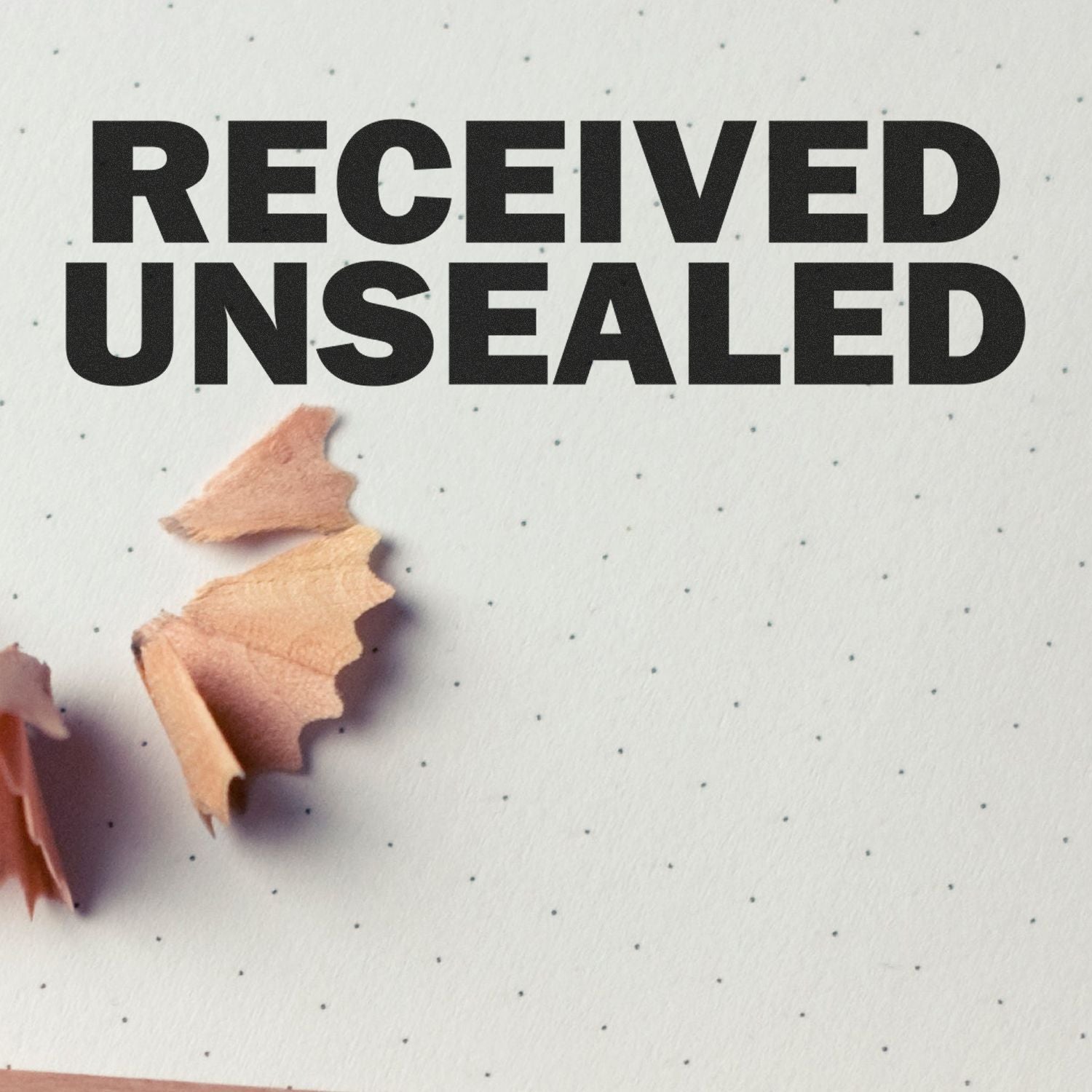 Received Unsealed Rubber Stamp impression on dotted paper with pencil shavings nearby.