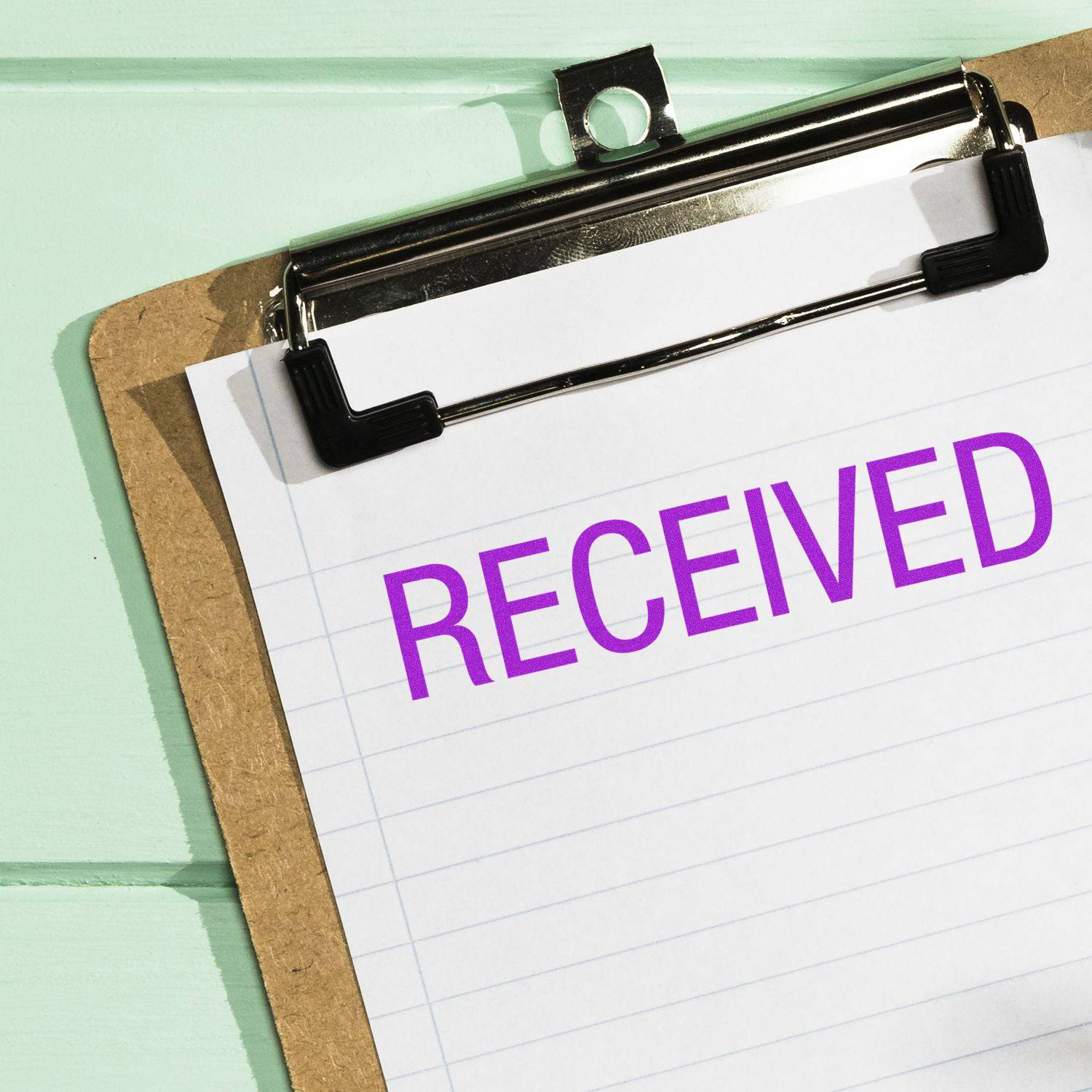 Clipboard with paper stamped RECEIVED in purple ink using the Large Received Rubber Stamp.