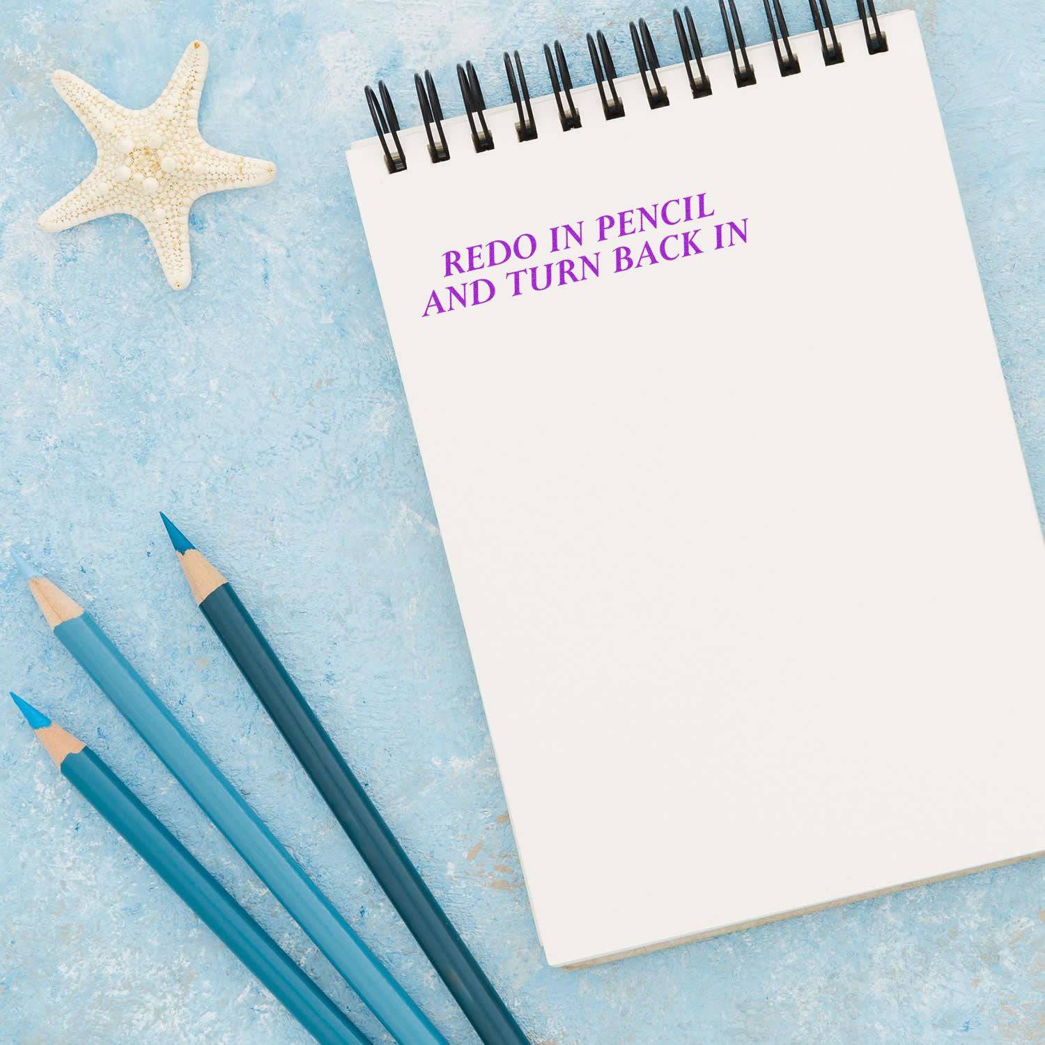 Large Redo In Pencil And Turn Back In Rubber Stamp on a spiral notebook with blue pencils and a starfish on a blue textured background.