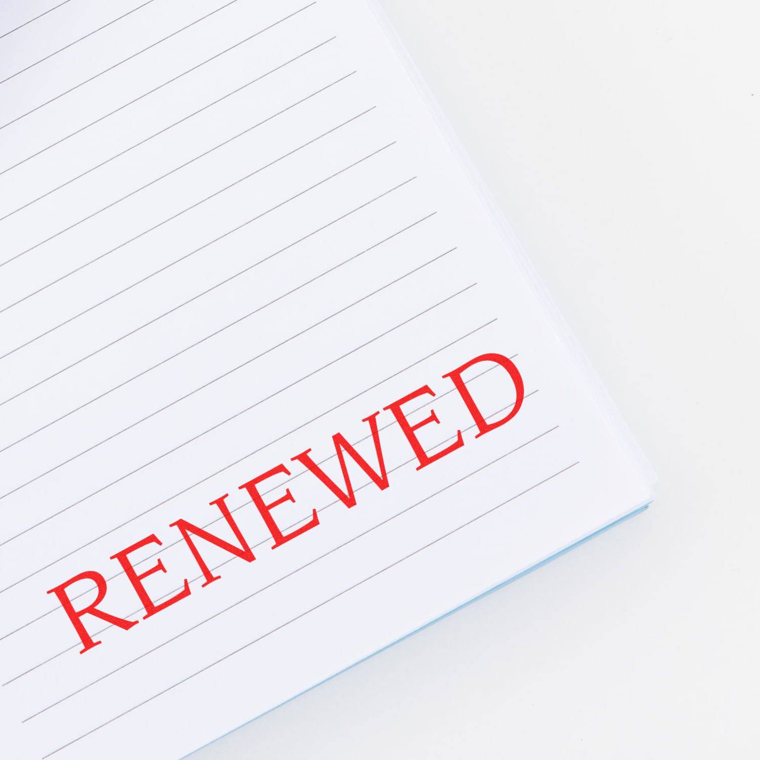 Large Renewed Rubber Stamp in red ink used on a lined notebook, displaying the word RENEWED prominently on the page.