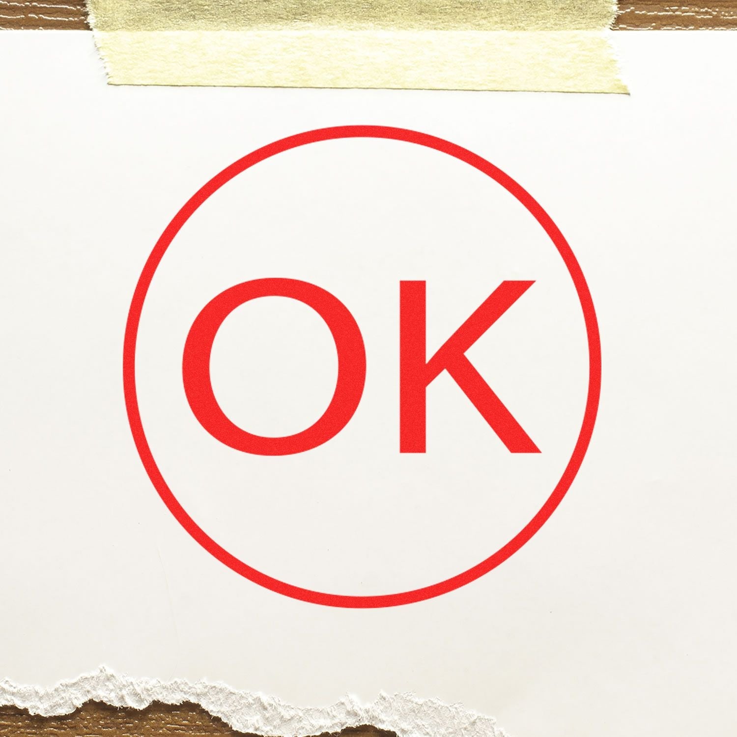 Self Inking Round OK Stamp in red ink on white paper, taped at the top with masking tape, and torn edges at the bottom.