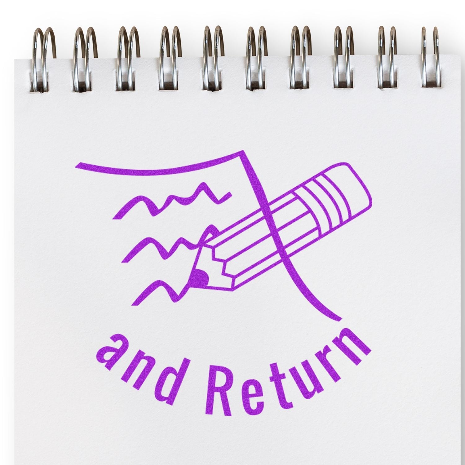 Self Inking Round Sign and Return Stamp in purple ink on a spiral notebook, featuring a pencil and wavy lines design.
