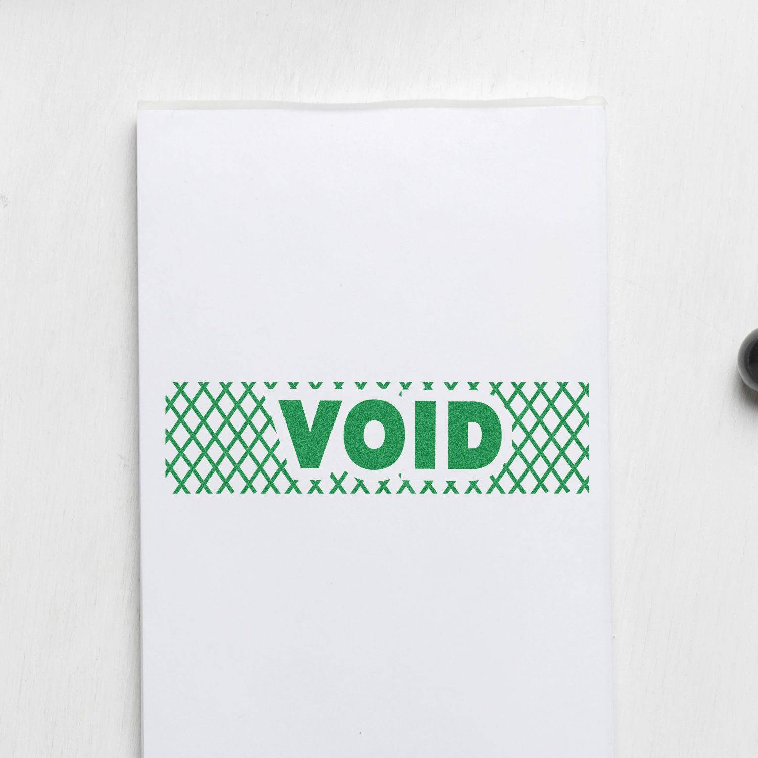Large Pre-Inked Void with Strikelines Stamp in green ink on white paper, showing the word VOID with a grid pattern background.
