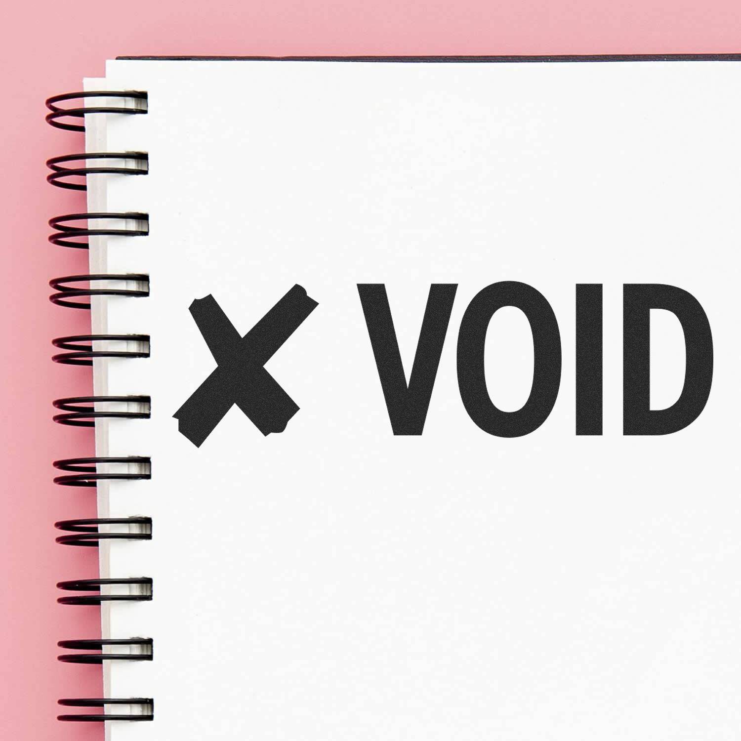 Large Pre-Inked Void with X Stamp used on a white spiral notebook, showing a bold X and the word VOID on a pink background.