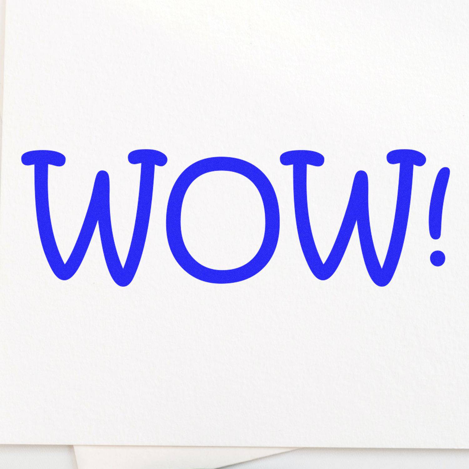 Large Pre-Inked Wow Stamp in use, leaving a bold blue WOW! impression on white paper.